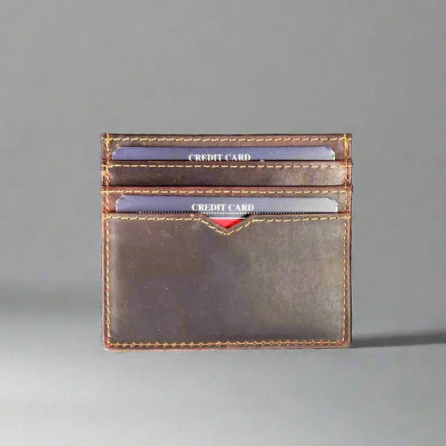 Brown leather card holder wallet with visible credit cards on a gray background
