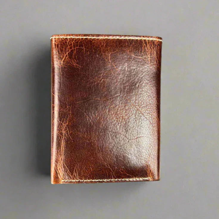 Brown leather wallet with a distressed finish on a gray background