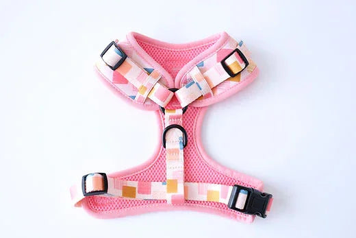 Pink mesh dog harness with colorful geometric straps and black plastic buckles on white background
