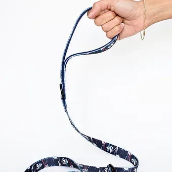 Hand holding navy blue patterned dog leash against white background