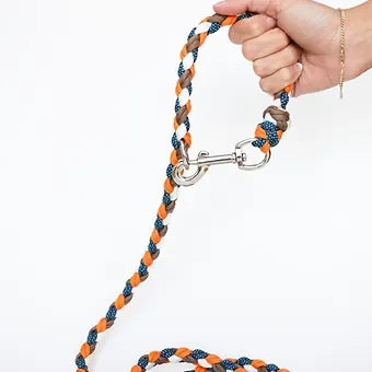 Hand holding braided orange, blue, and tan rope dog leash with metal clasp
