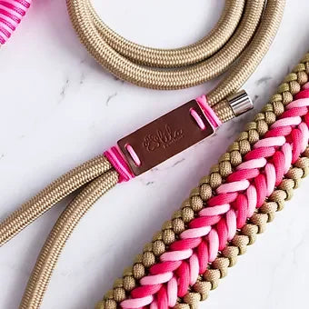 Beige and pink braided rope dog leash with leather label on white marble surface