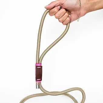 Hand holding beige rope dog leash with leather and pink accent on white background