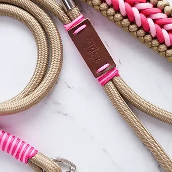 Beige and pink braided rope dog leash with leather tag on white background