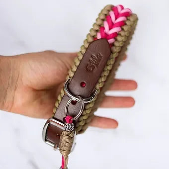 Hand holding a braided khaki and pink paracord dog collar with leather accents