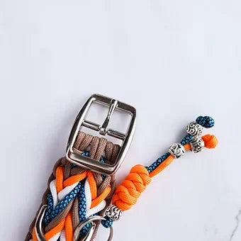 Woven paracord dog collar with silver buckle, orange, blue, and white cords on white background