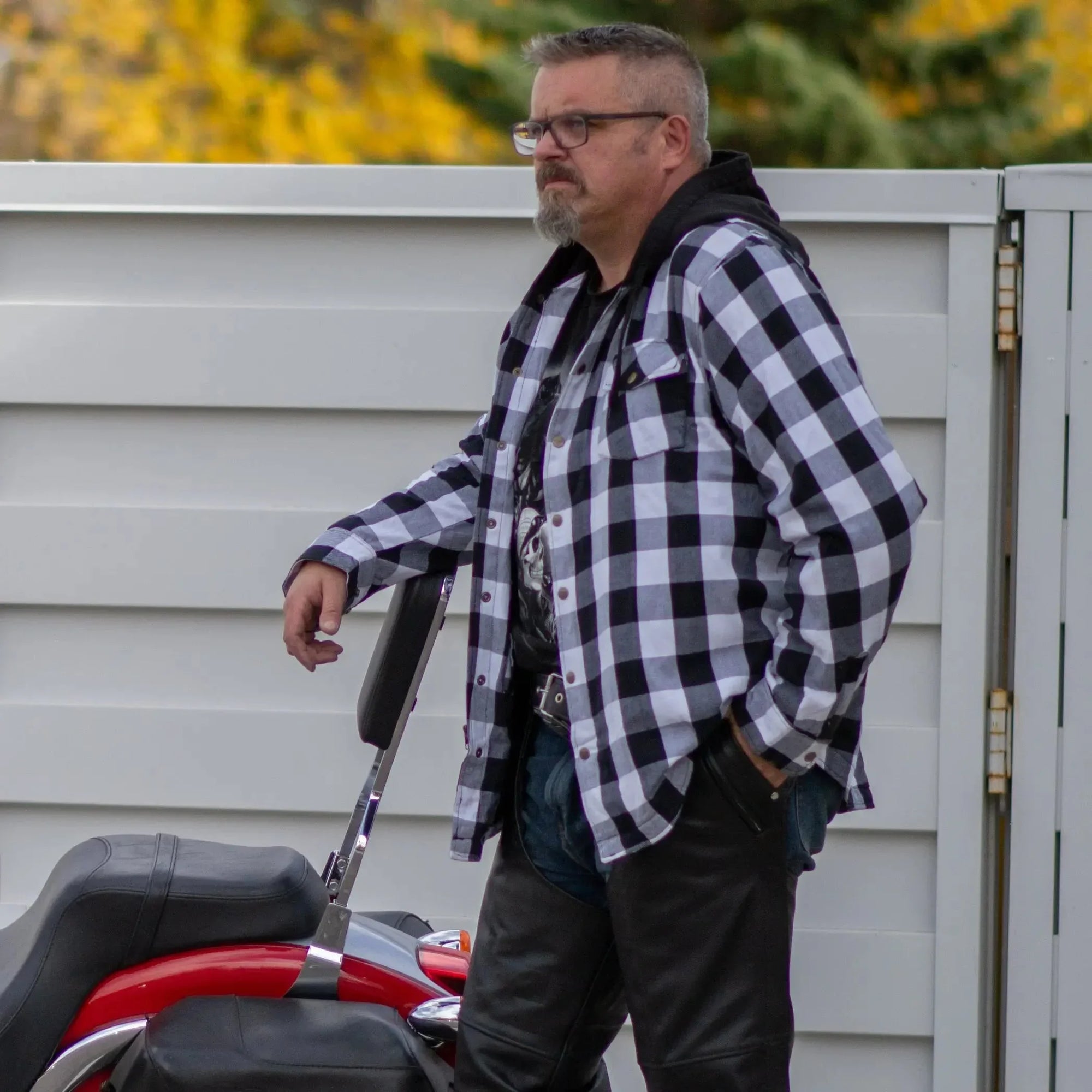 Man wearing Milwaukee Leather men's plaid flannel armored shirt jacket by red motorcycle