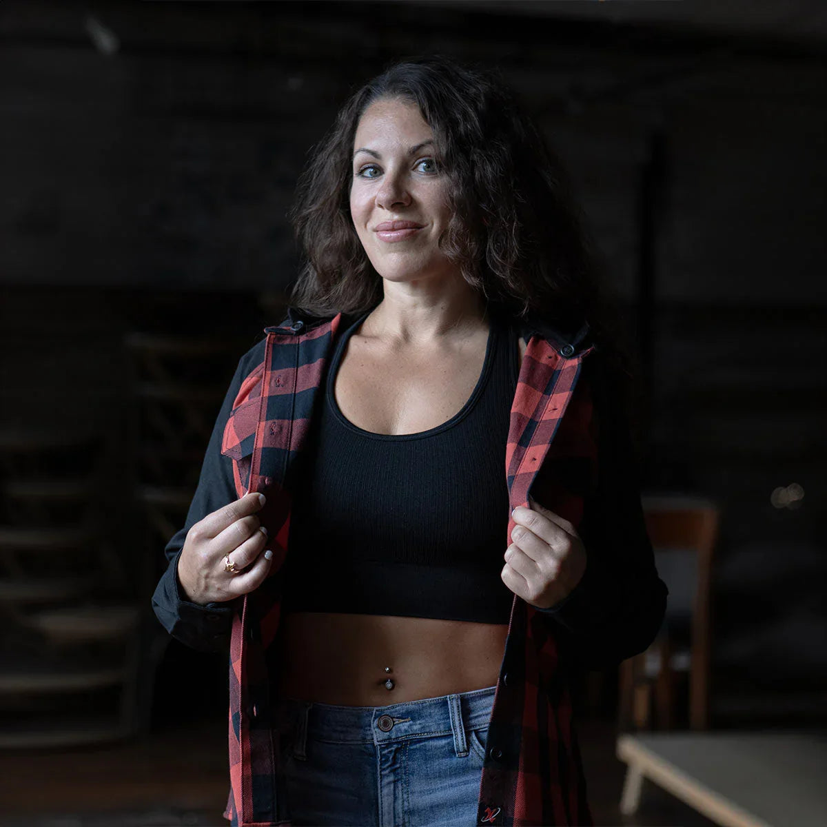 Woman in red plaid jacket, black crop top, blue jeans, indoors, casual fashion