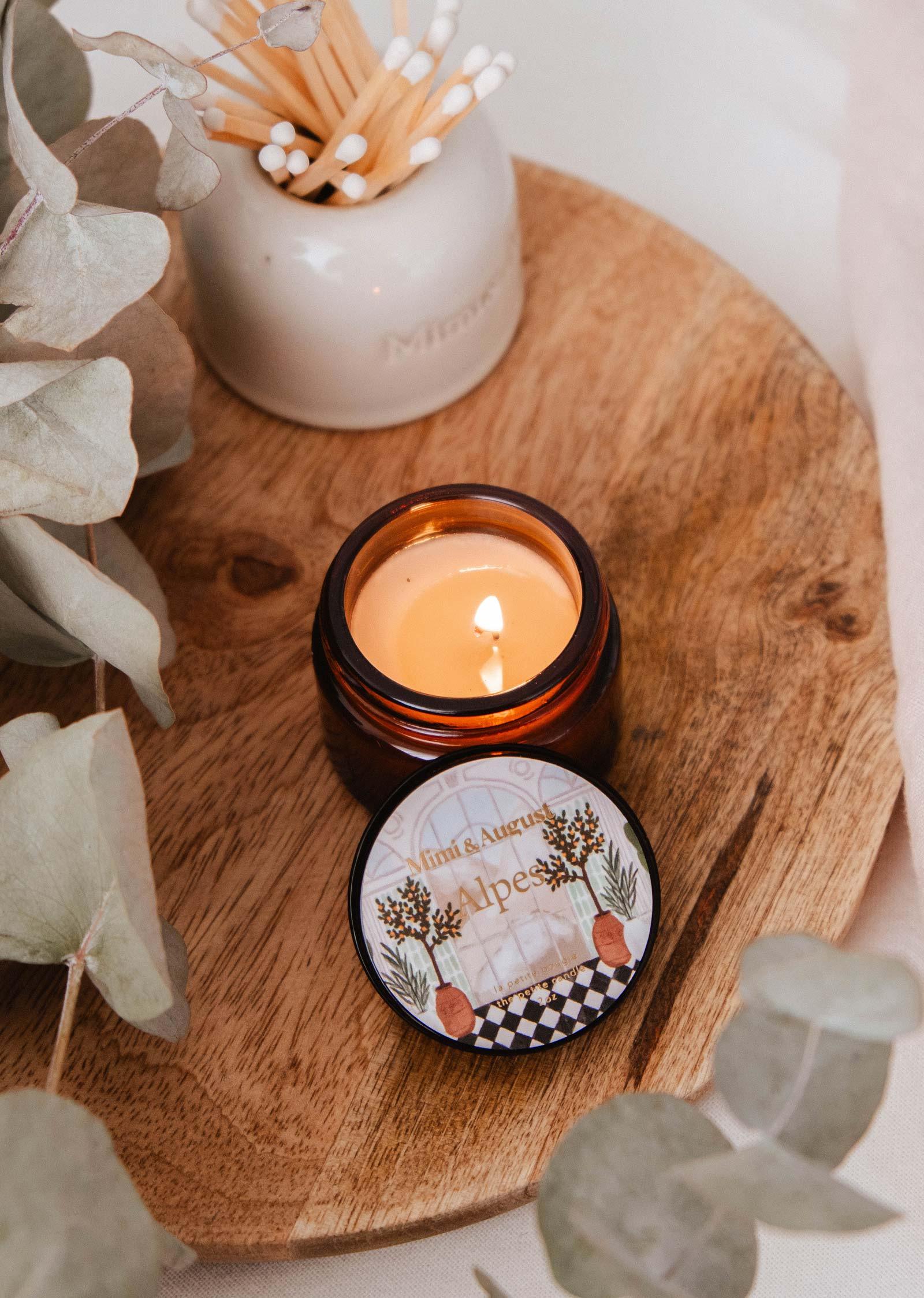 Mimi and August Alpes mini candle lit in amber jar on wooden tray, with matches and eucalyptus
