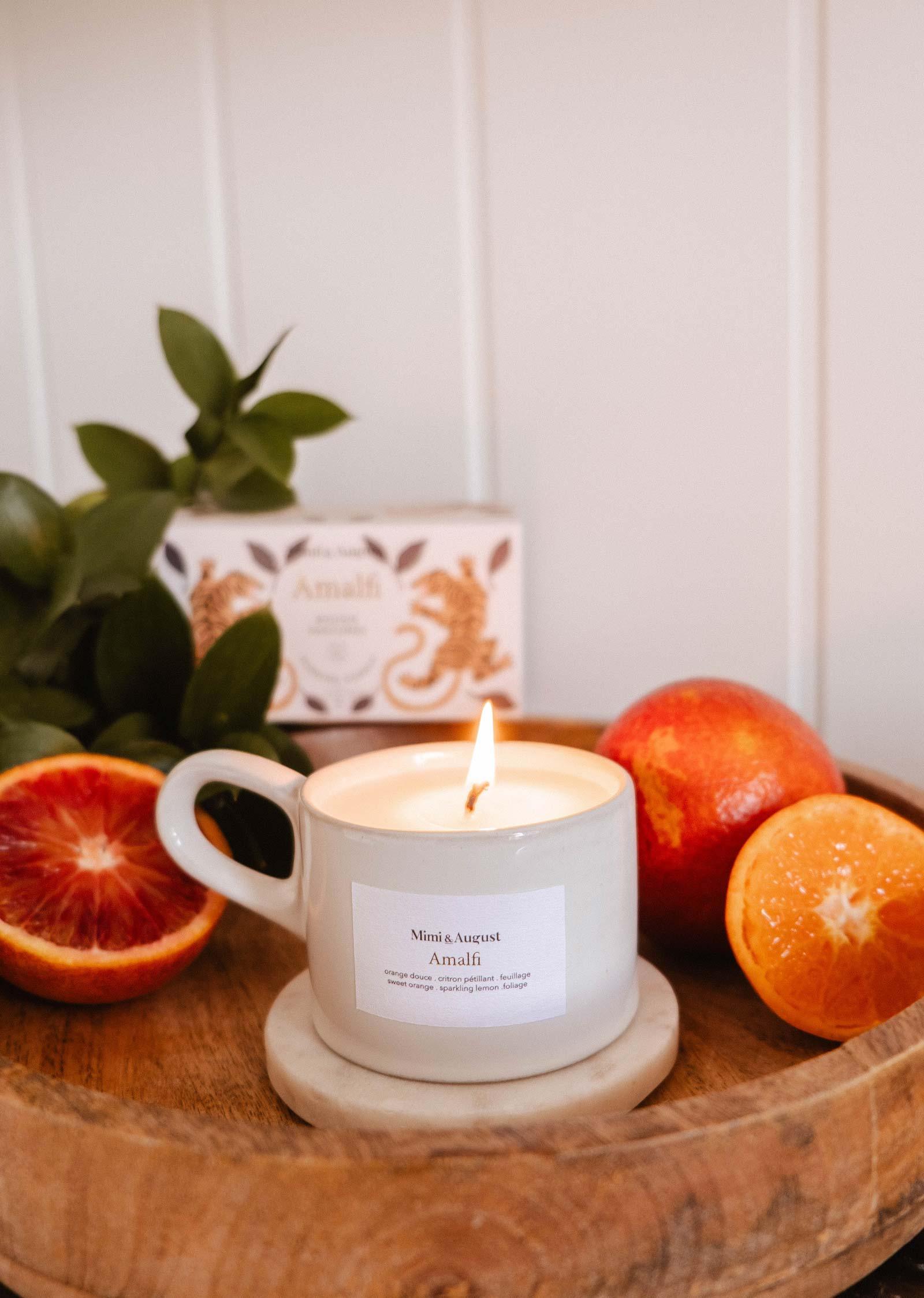 Amalfi reusable candle in white cup on wood tray with sliced oranges and green leaves