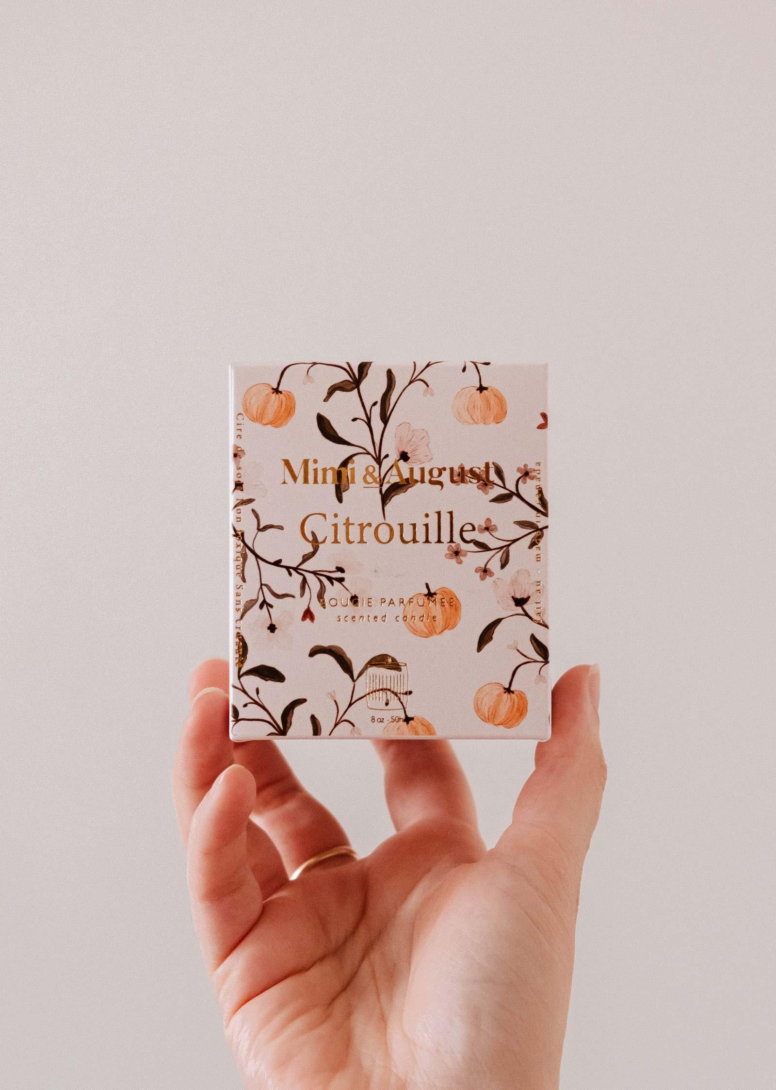 Hand holding Mimi & August Citrouille soy wax candle box with pumpkin design