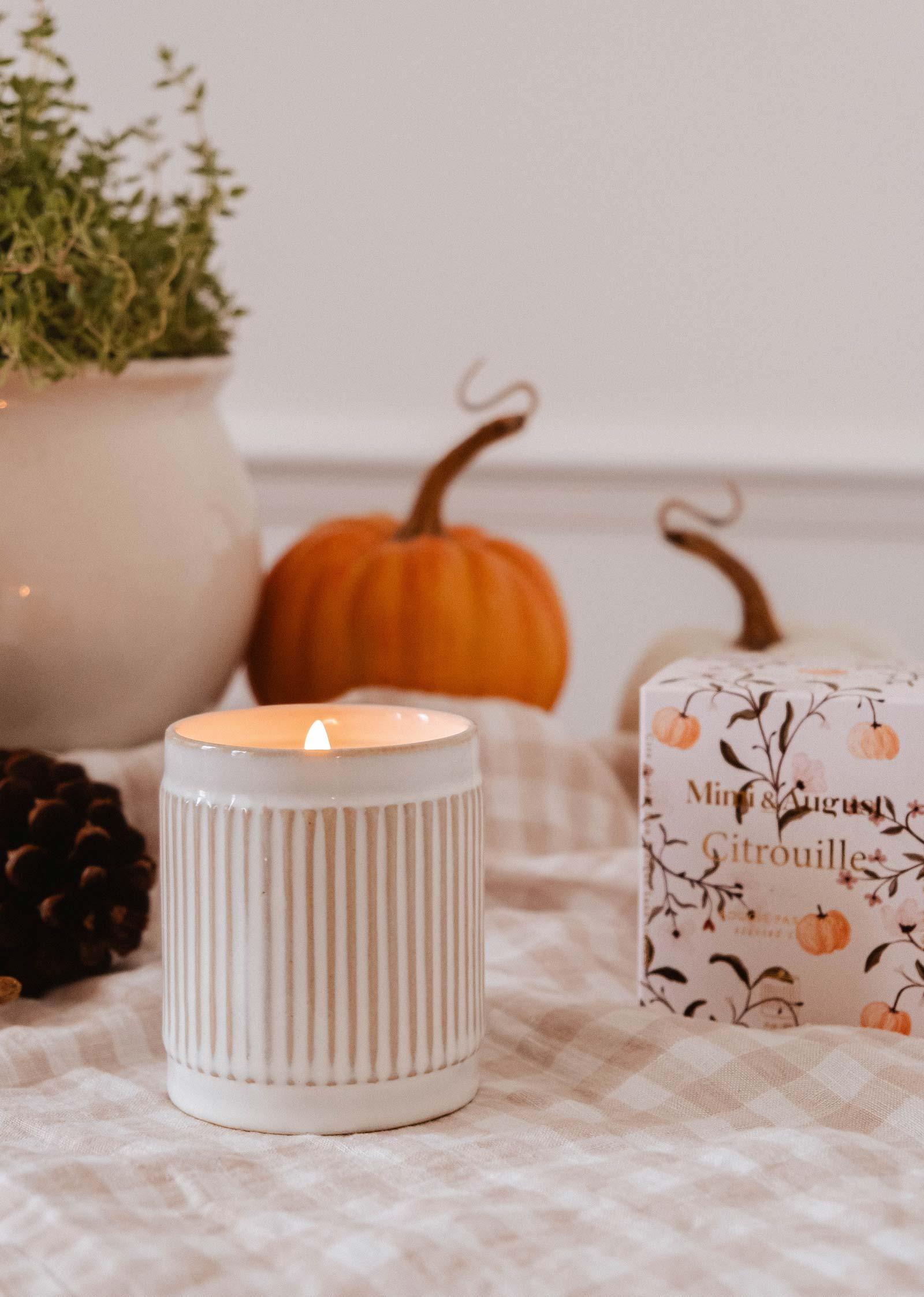 Citrouille soy wax candle in ribbed white jar, with pumpkins and box on checkered tablecloth