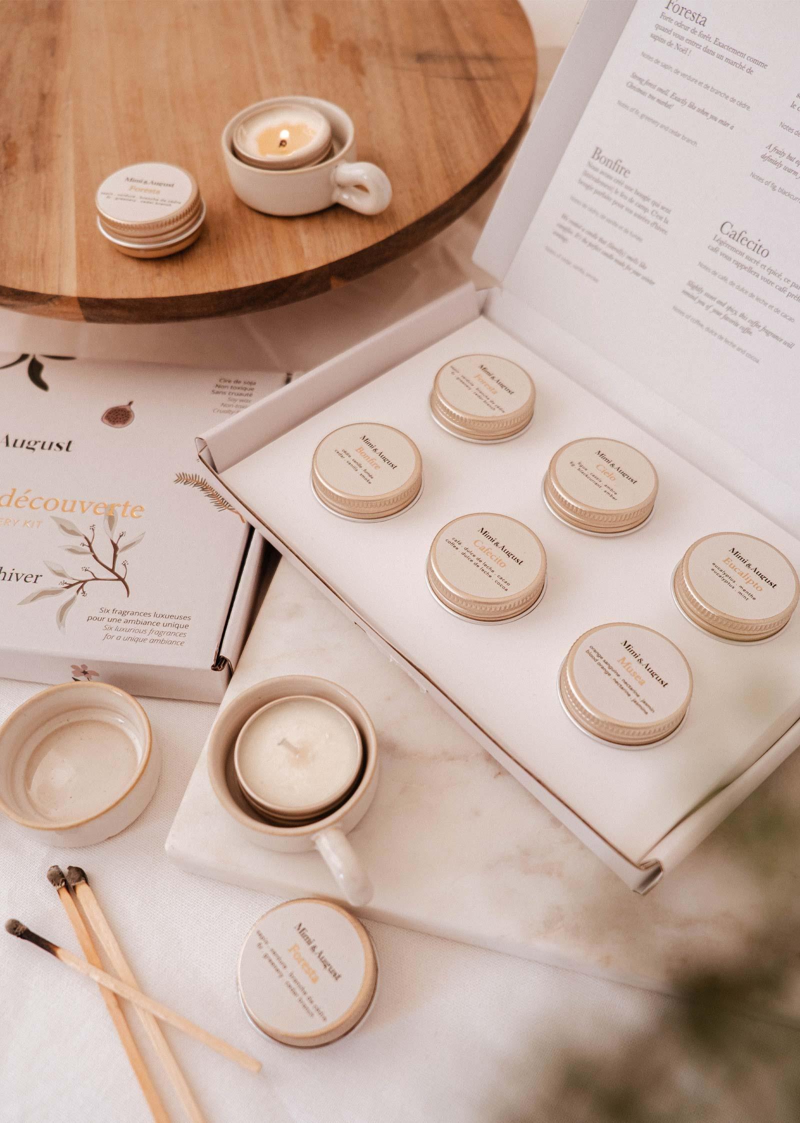 Discovery kit of Mimi and August fall winter candles with tin jars, cup, and matches on table.