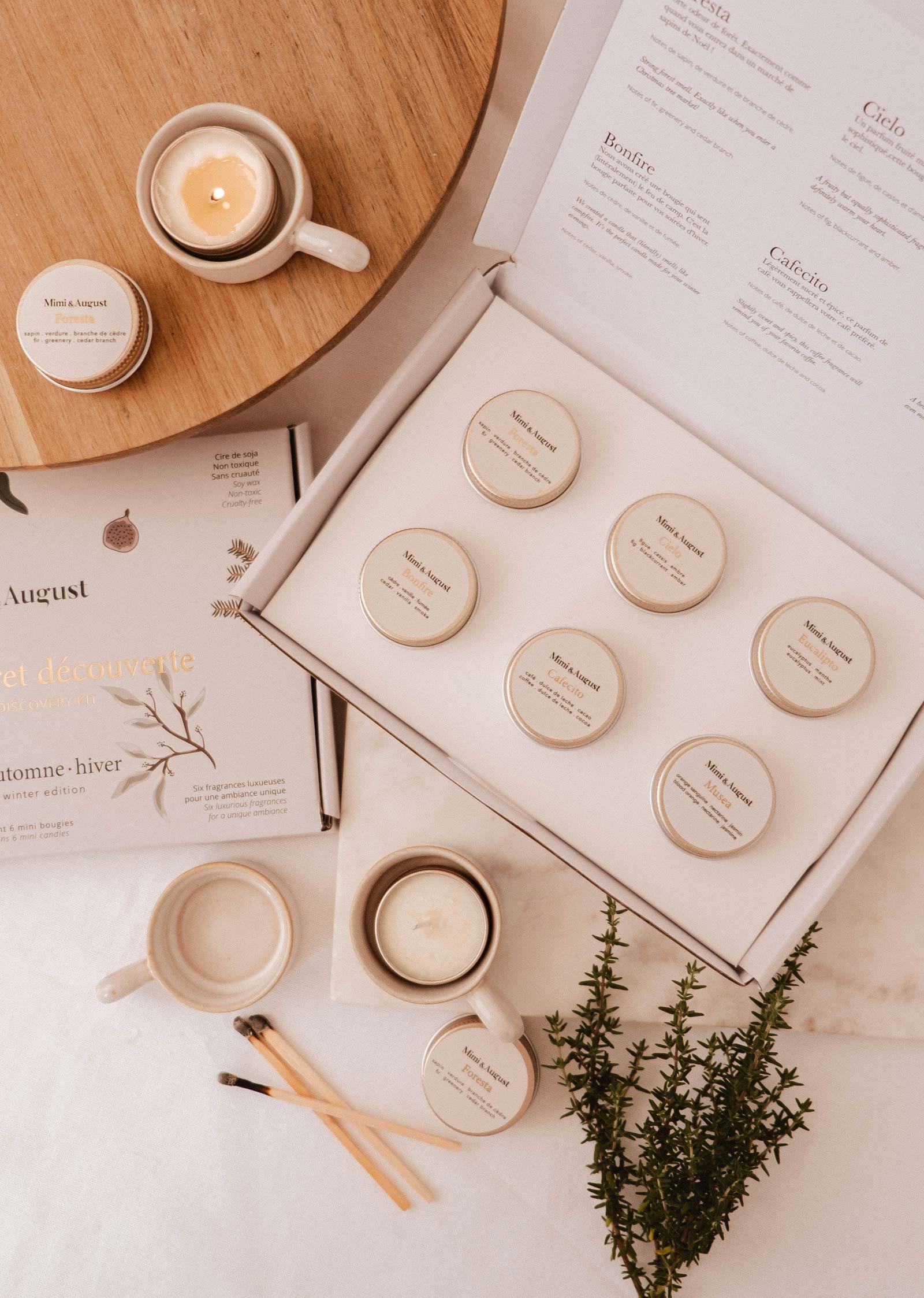 Mimi & August fall winter discovery kit with six mini candles, mugs, and herbs on a wooden table.