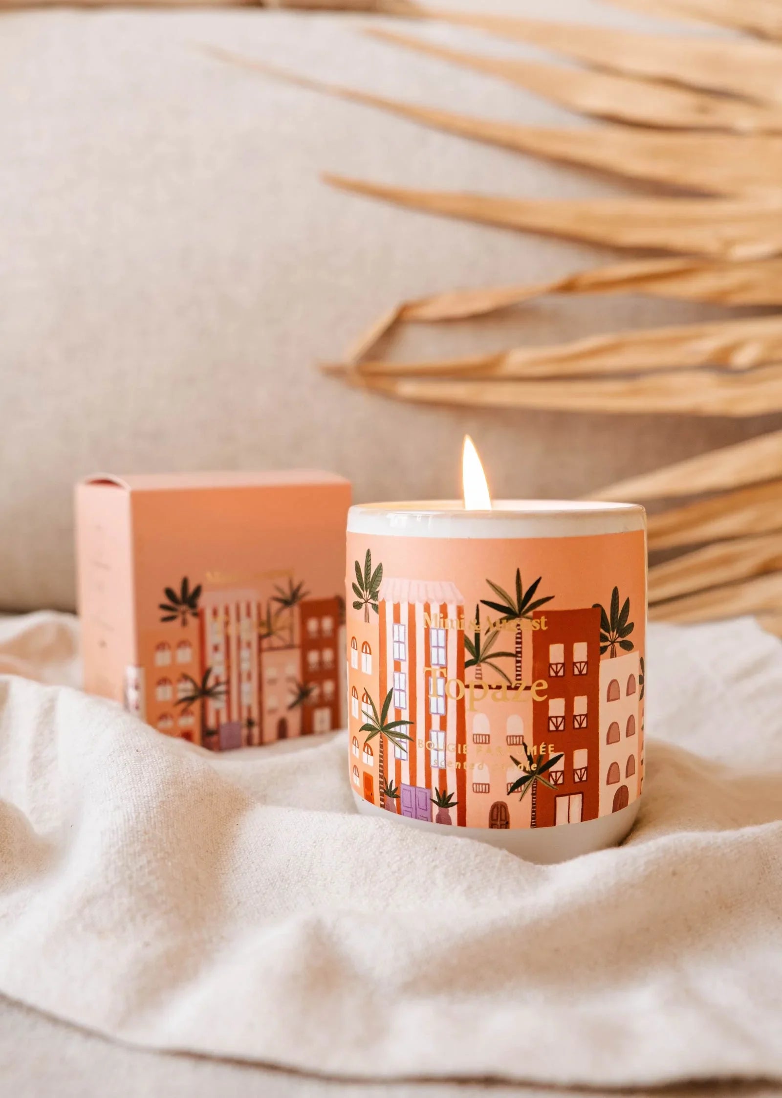 Topaze reusable 8oz candle by Mimi & August, lit, with decorative city print and matching box
