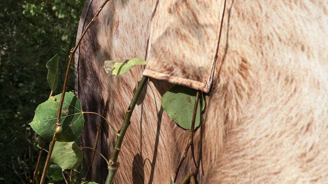 Close-up of camo hunting blind fabric with leaf and branch pattern outdoors