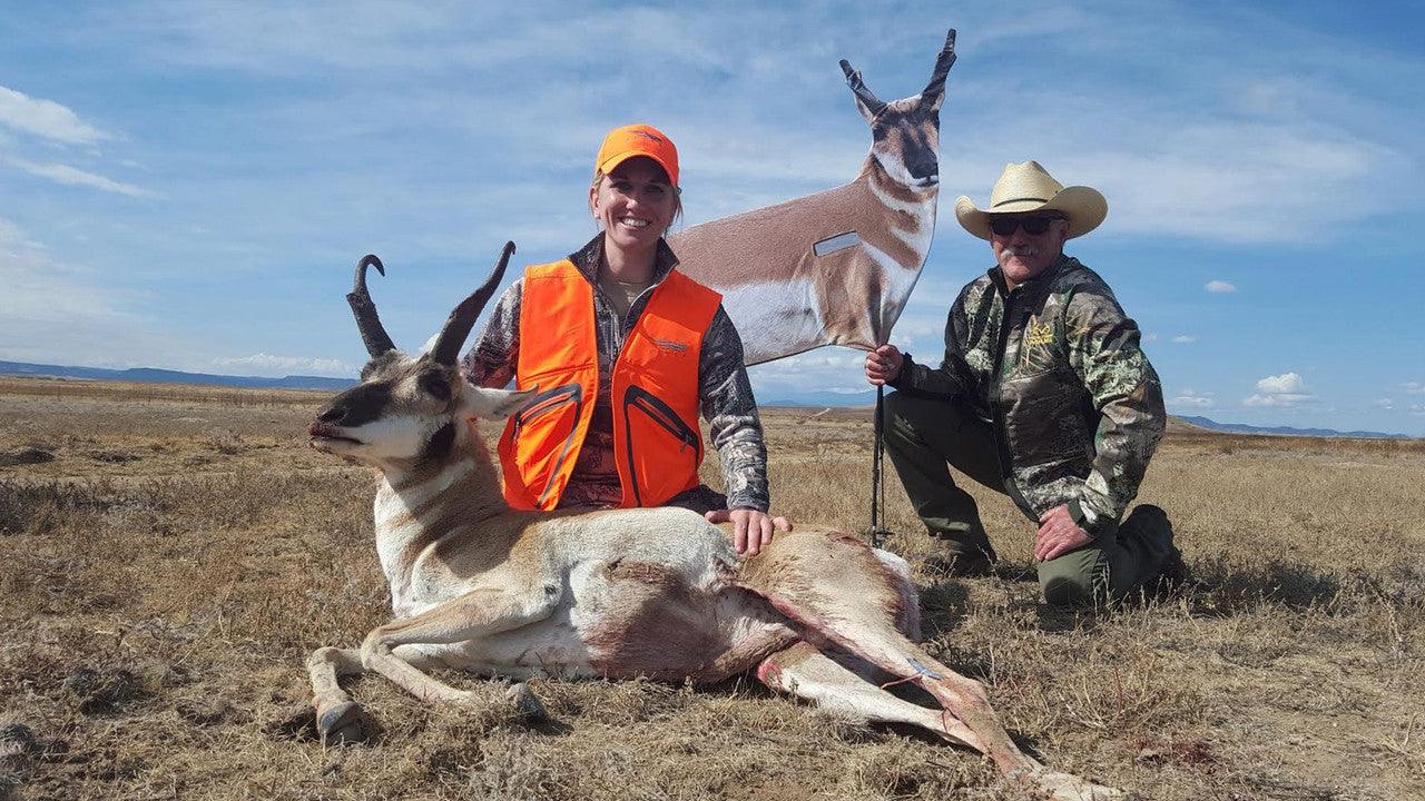 Hunters with pronghorn antelope and antelope decoy in open grassland under blue sky