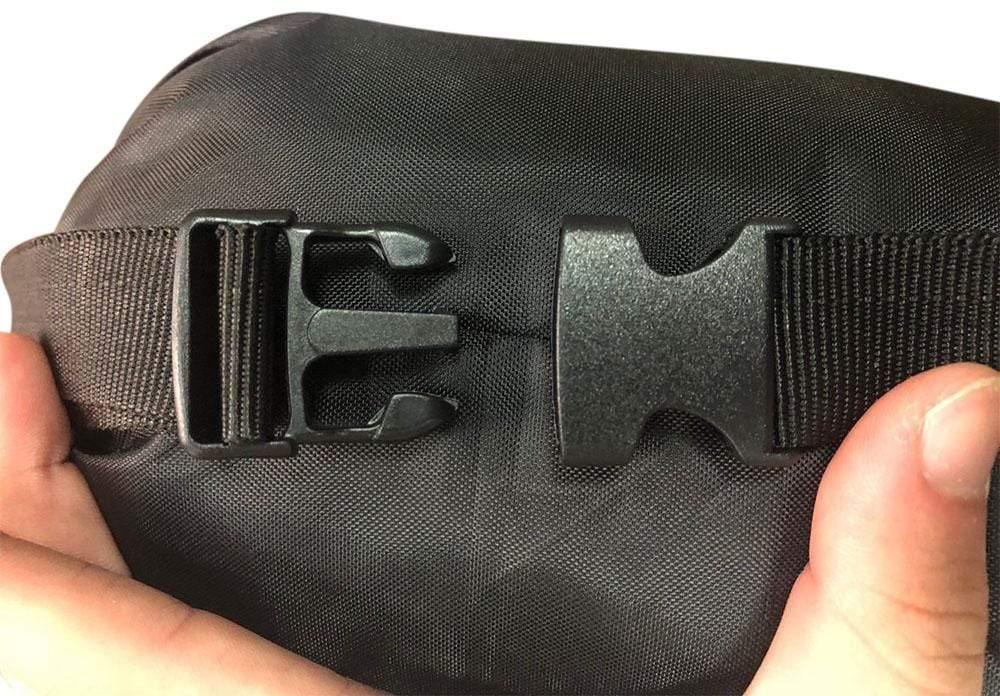 Close-up of black hammock storage bag with buckle strap held by hand