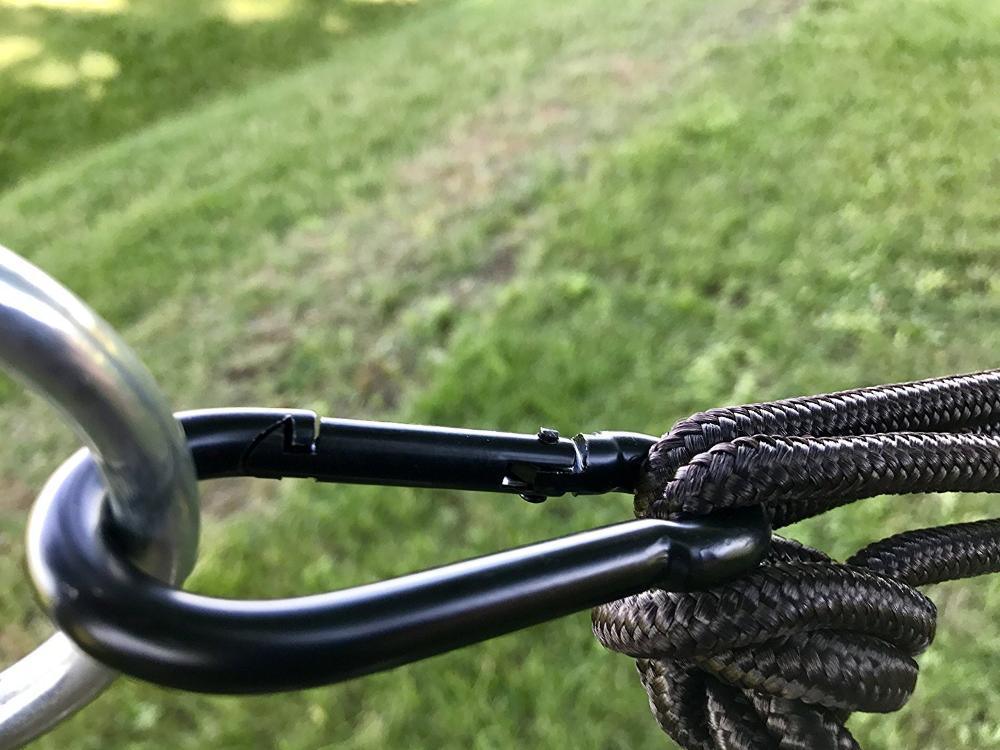 Close-up of hammock rope and carabiner connection outdoors on grass