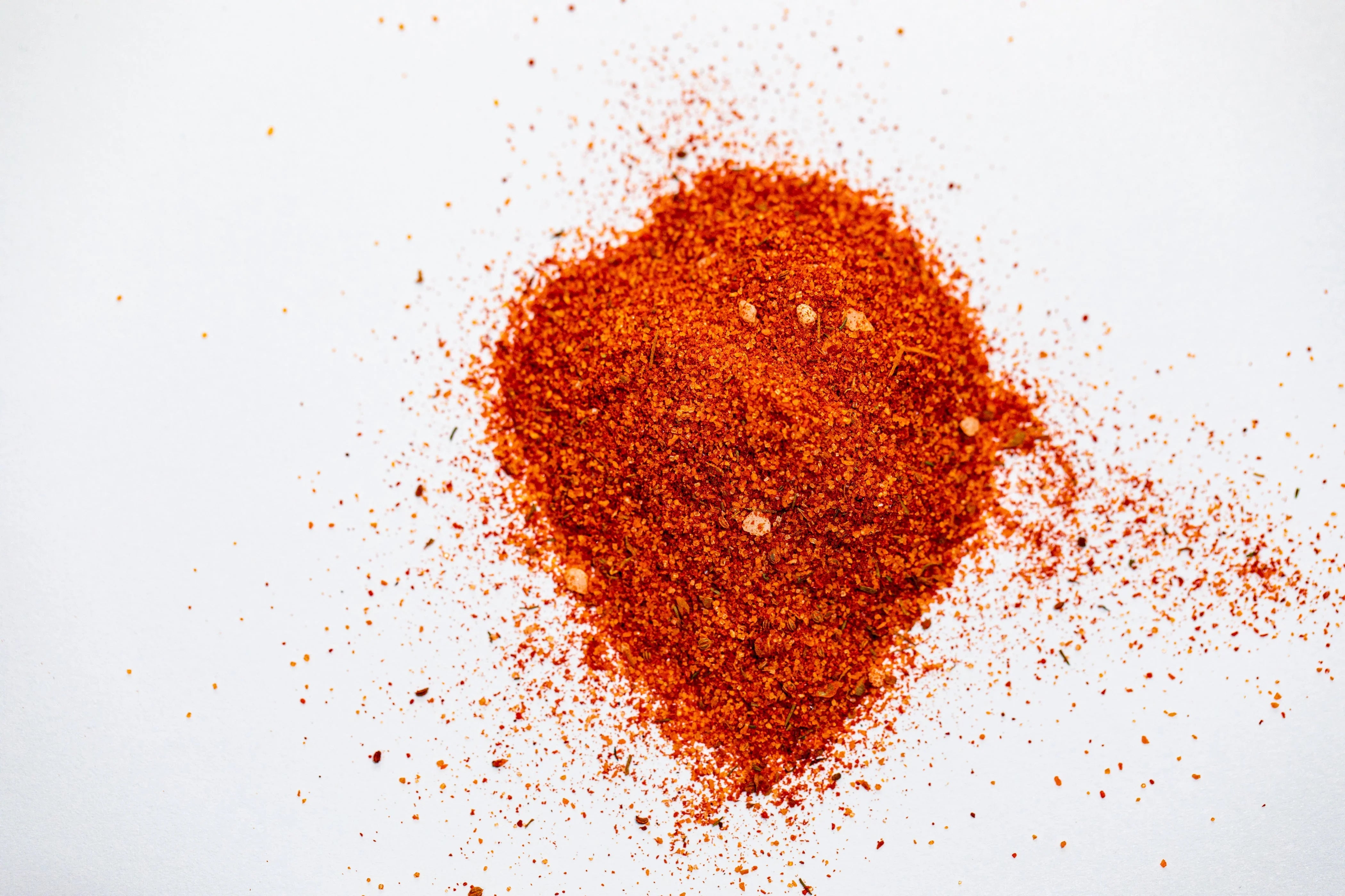 Pile of orange chicken seasoning rub on white background, finely ground spice blend