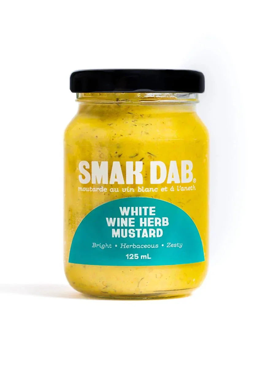 Jar of Smak Dab white wine herb mustard with blue label and black lid on white background.