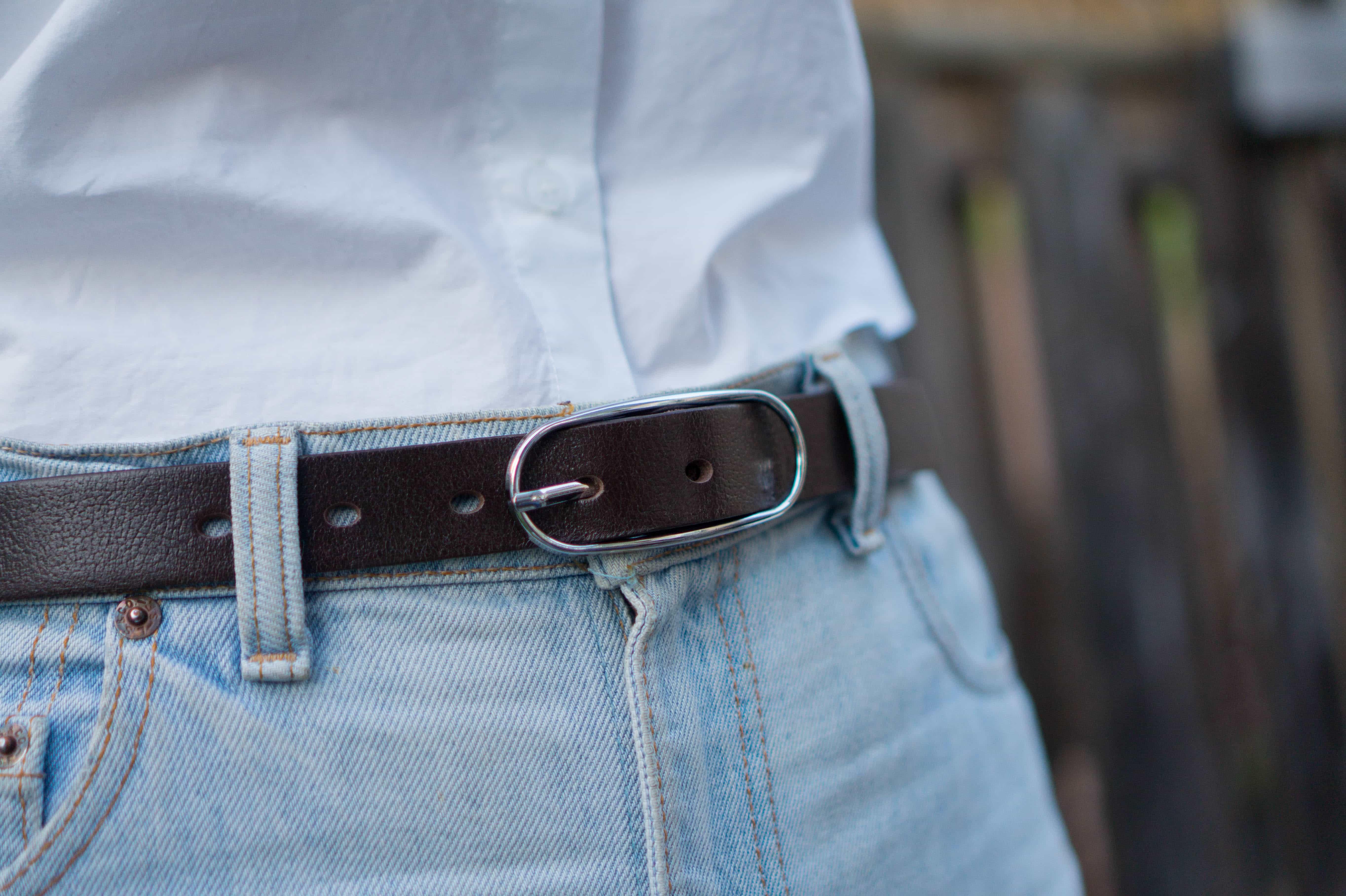 Brown leather belt with silver buckle on light blue jeans and white shirt