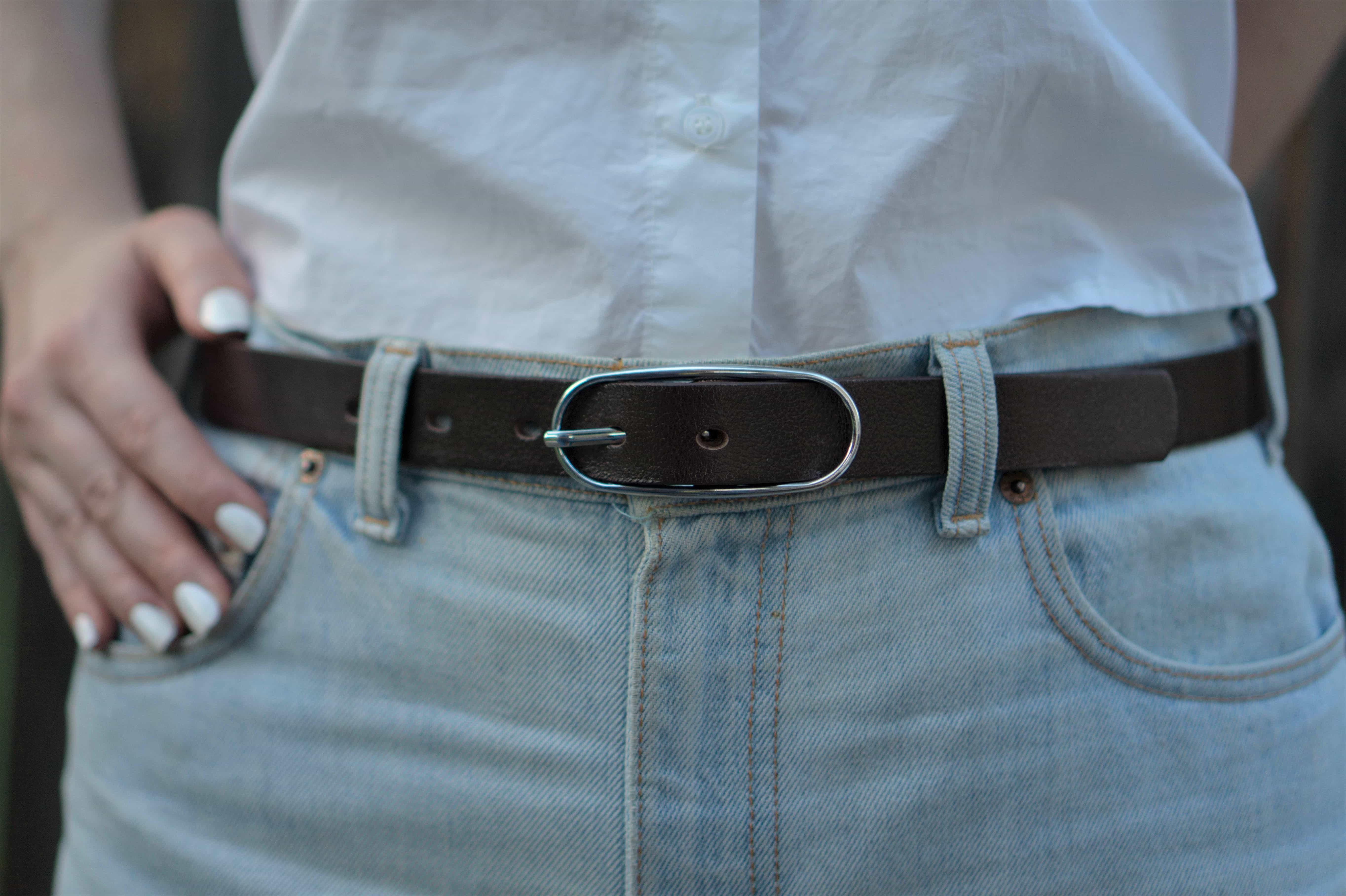 Brown leather belt with silver buckle on light denim jeans and white shirt