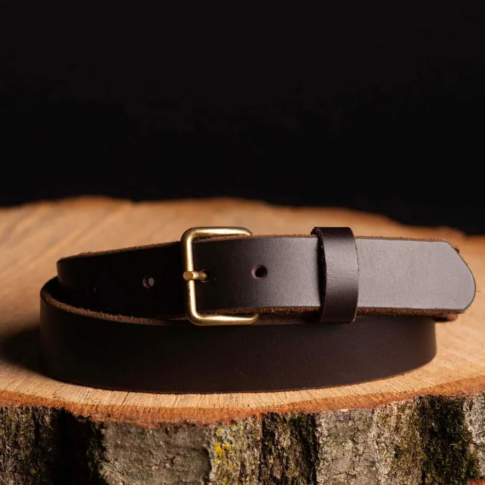 Dark brown leather belt with brass buckle on rustic wooden surface