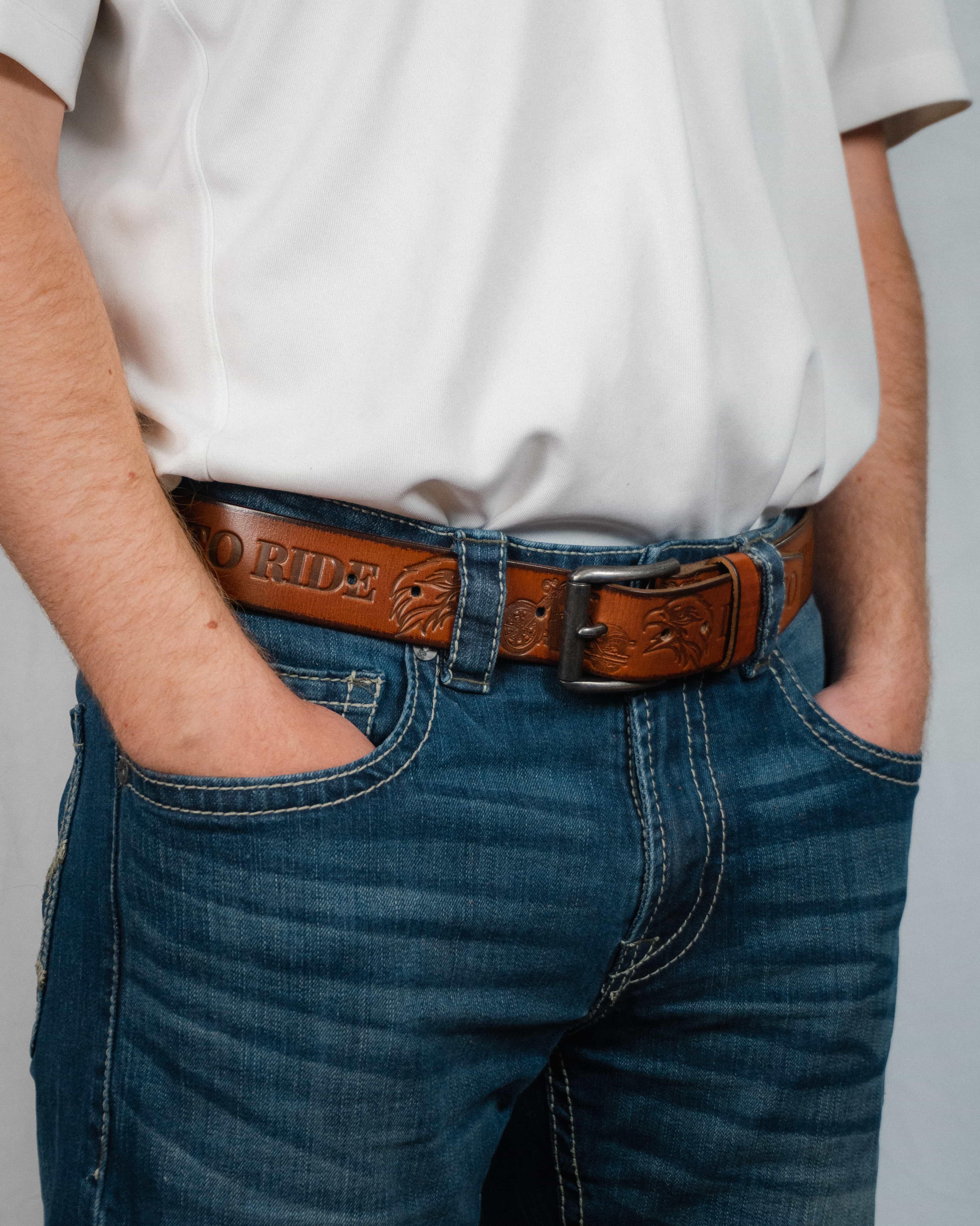 Man wearing blue jeans and a white shirt with a brown leather Western belt