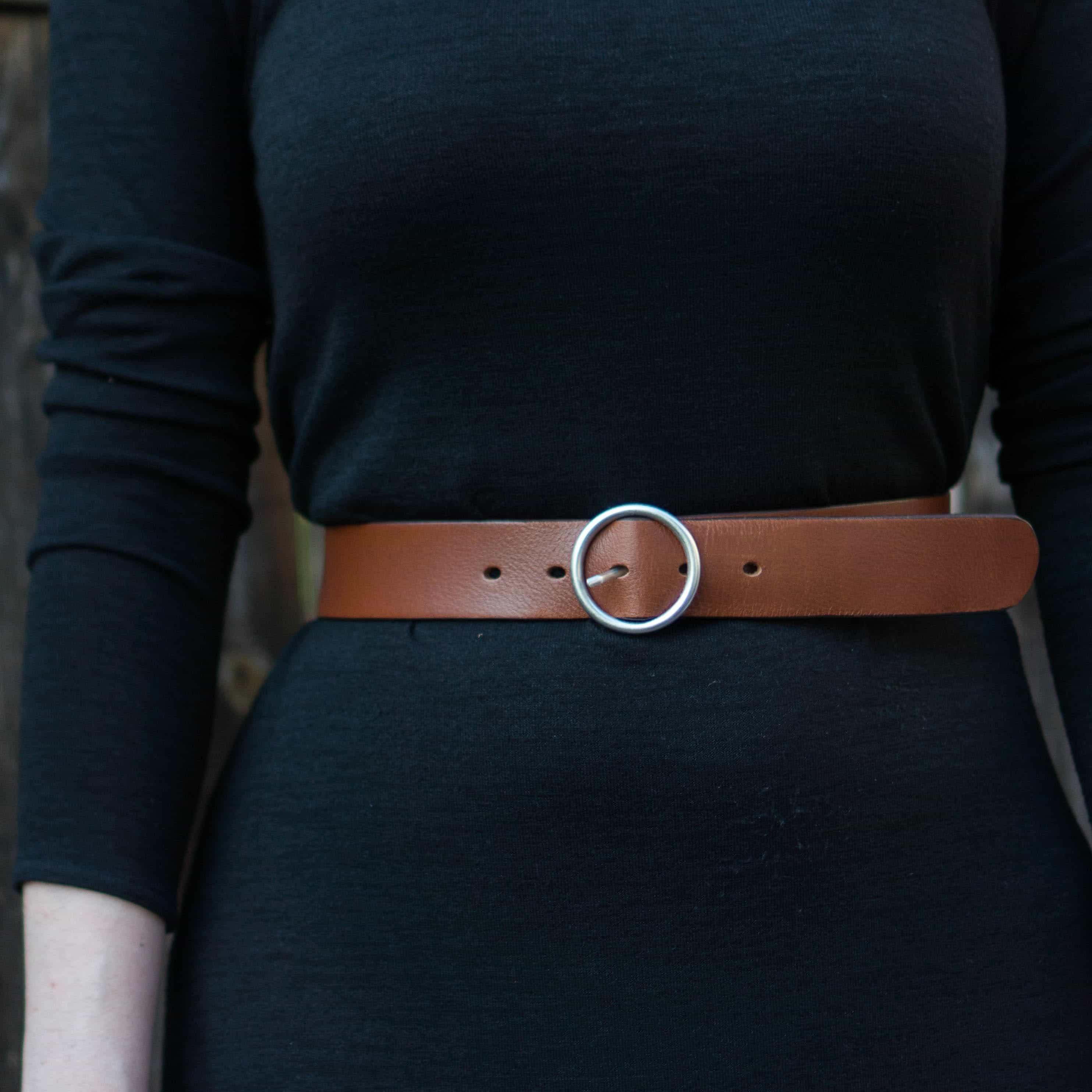 Brown leather belt with round silver buckle on black dress