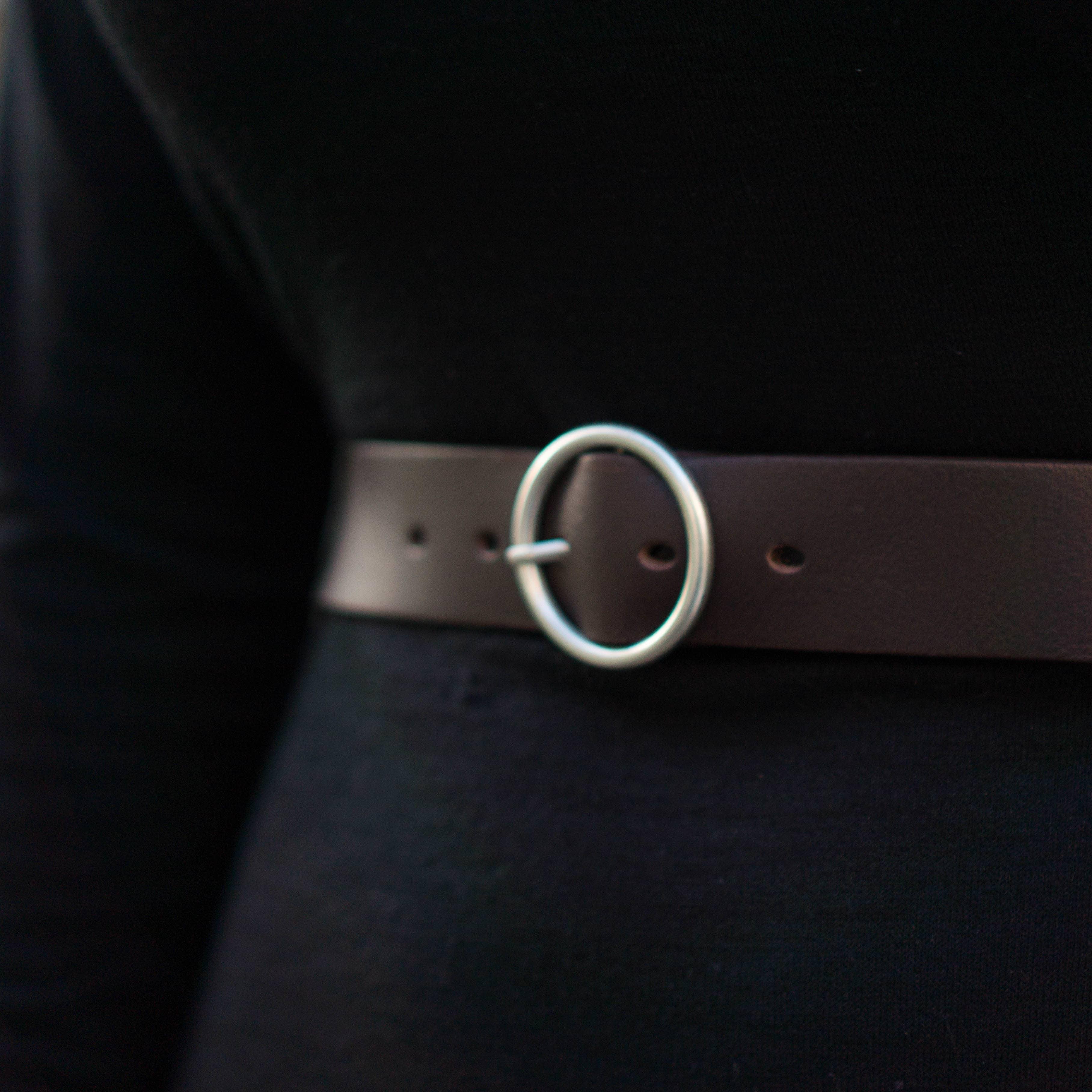 Brown leather belt with silver oval buckle on black outfit