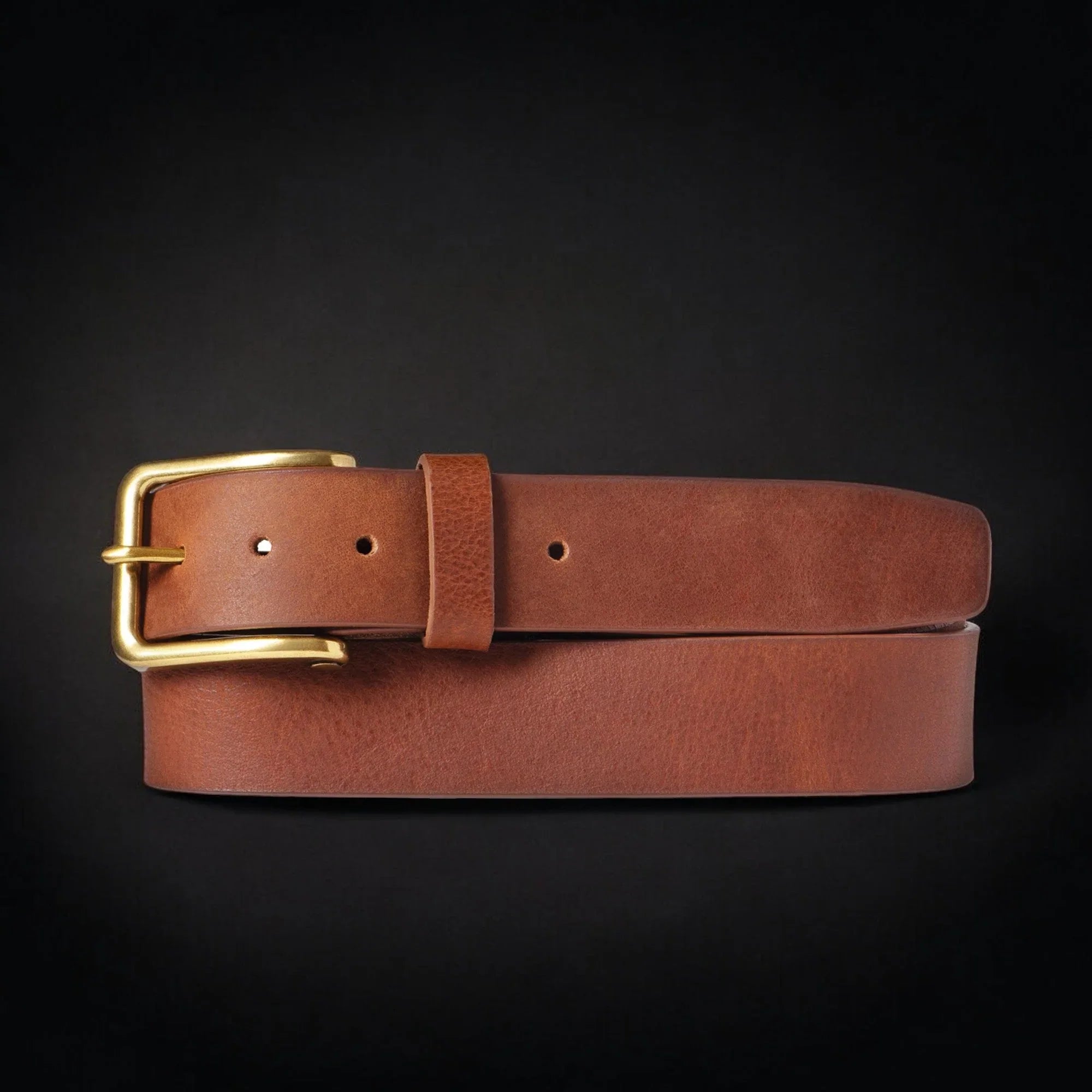 Brown leather belt with gold buckle on black background