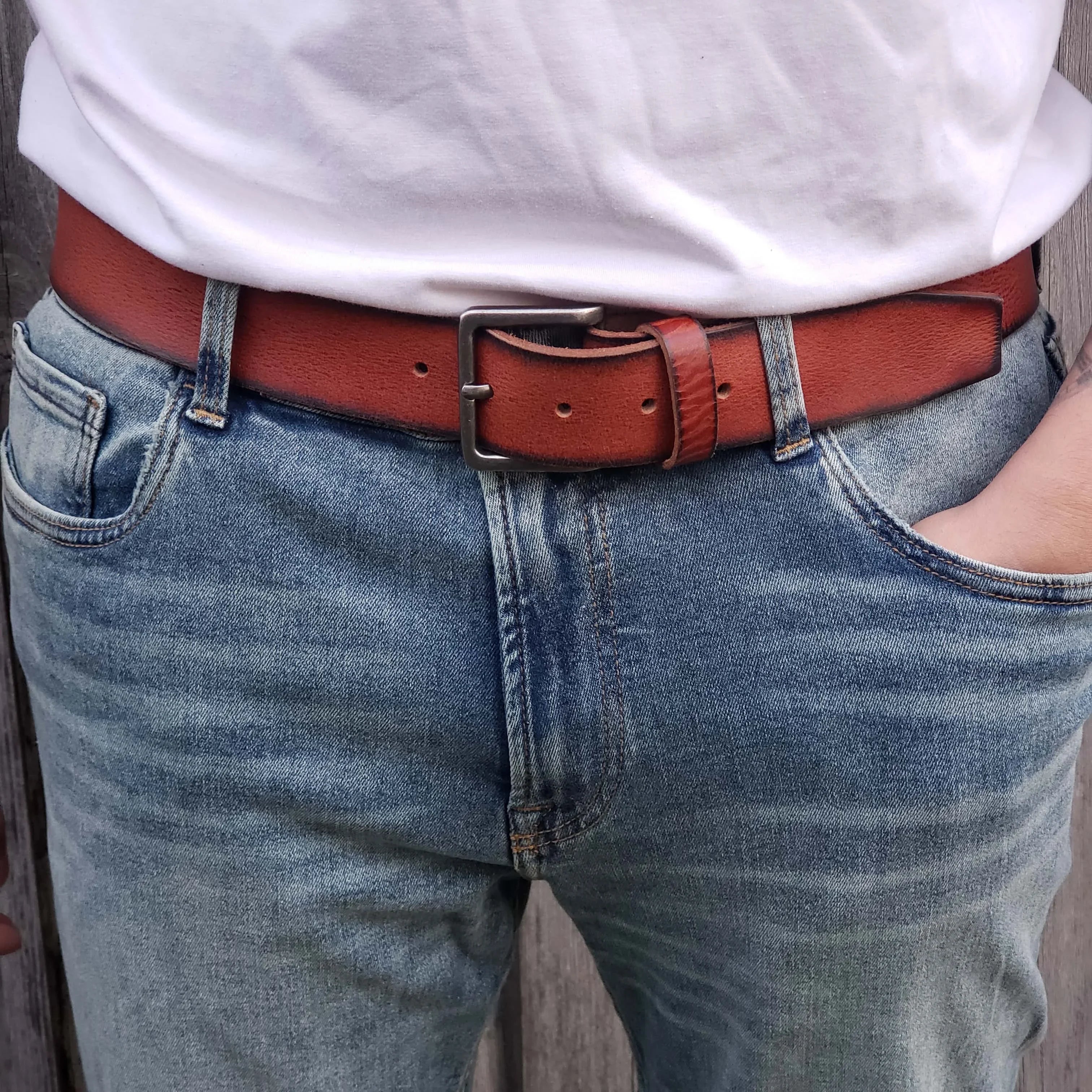 Brown leather belt with silver buckle on blue jeans and white t-shirt