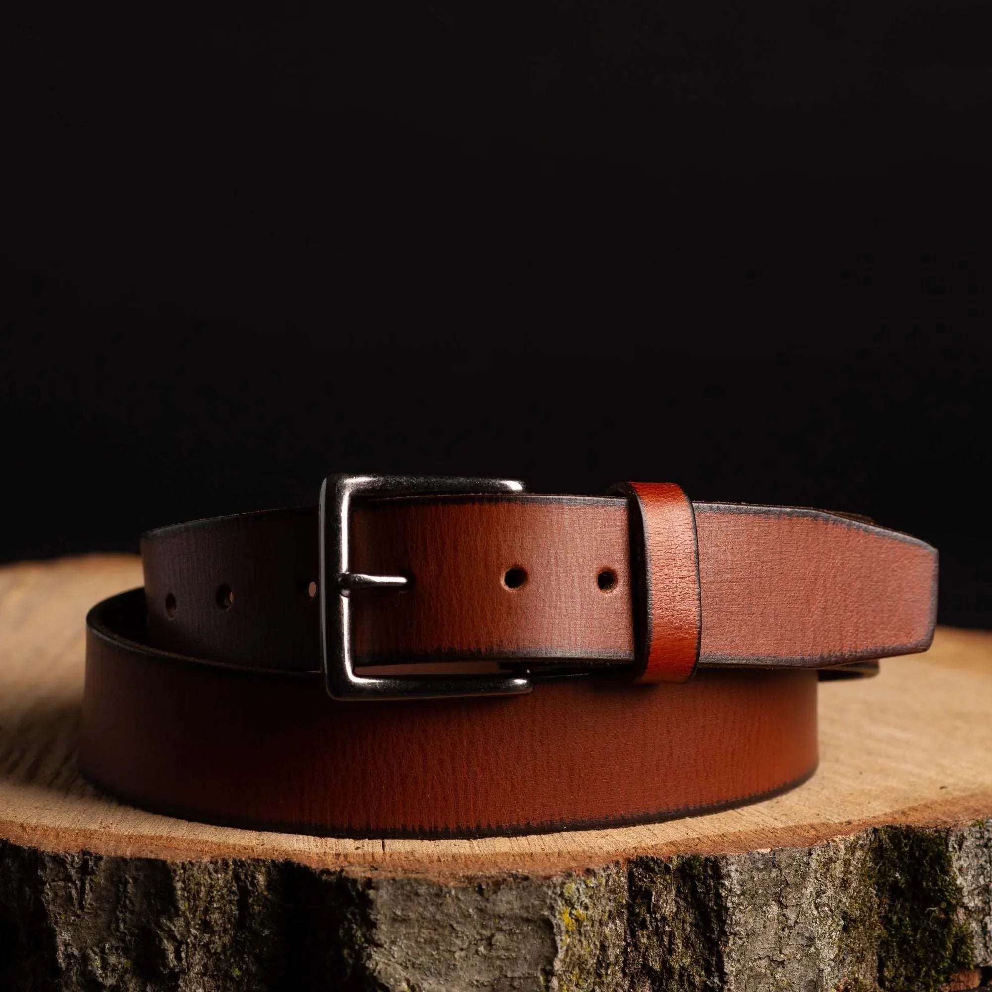 Brown leather belt with silver buckle on wooden surface, fashion accessory display