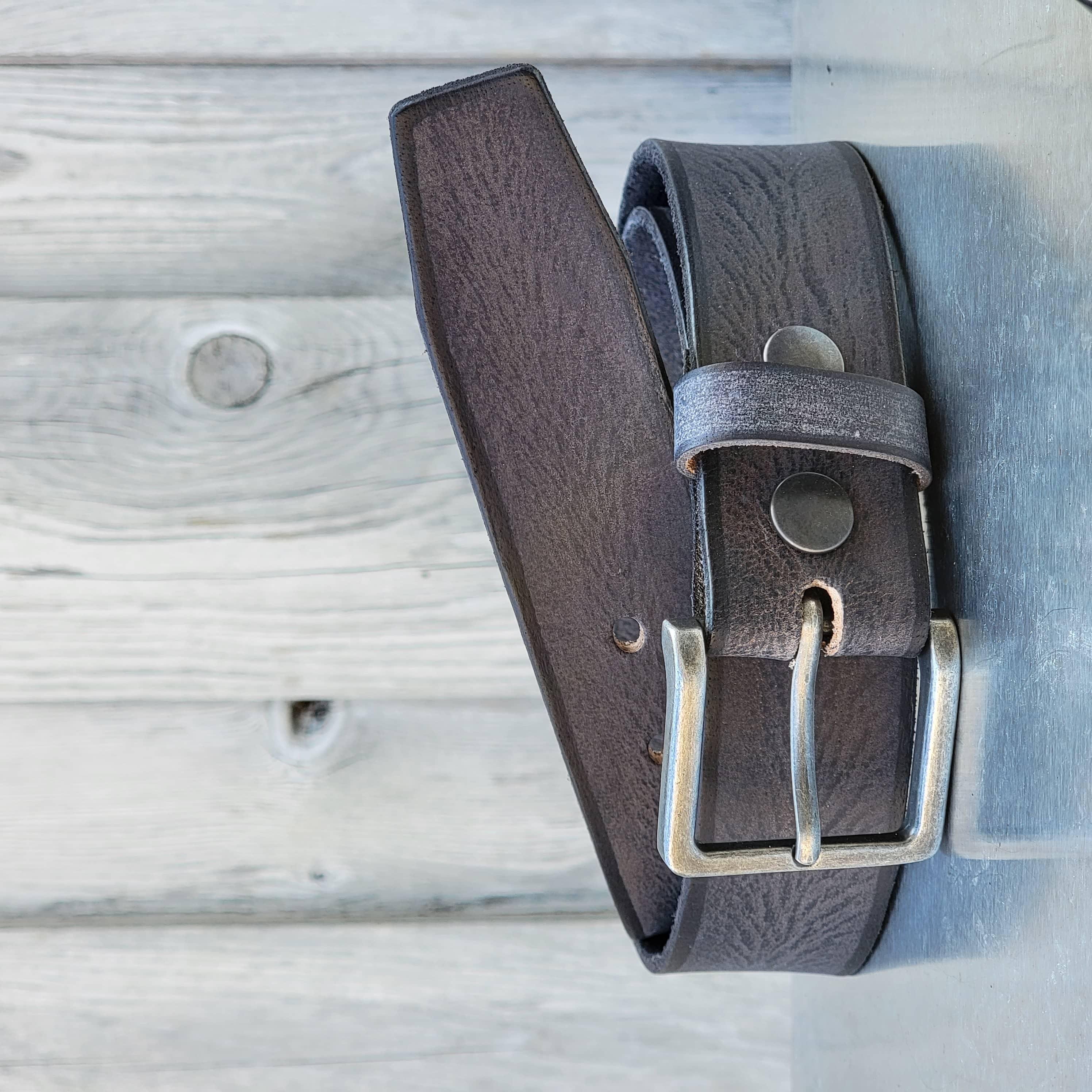 Brown leather belt with silver buckle on rustic wooden background