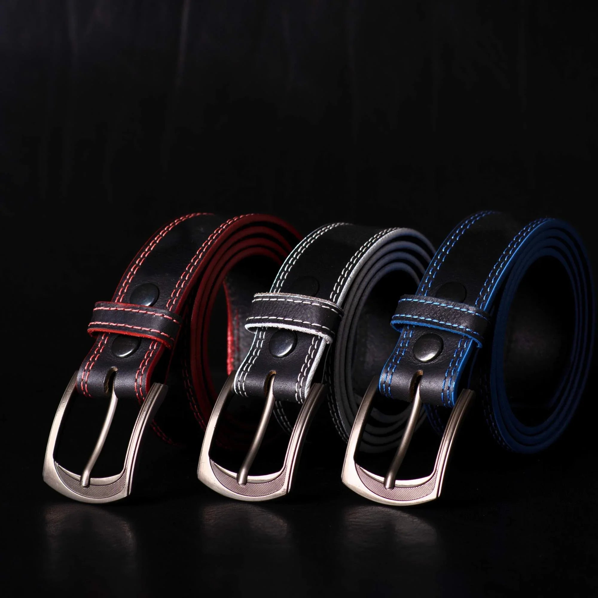 Three leather belts with red, white, and blue stitching on a black background