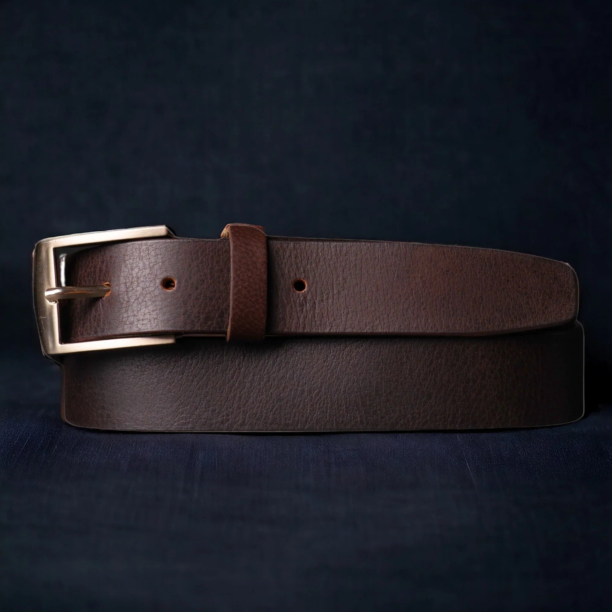 Dark brown leather belt with silver buckle on dark background