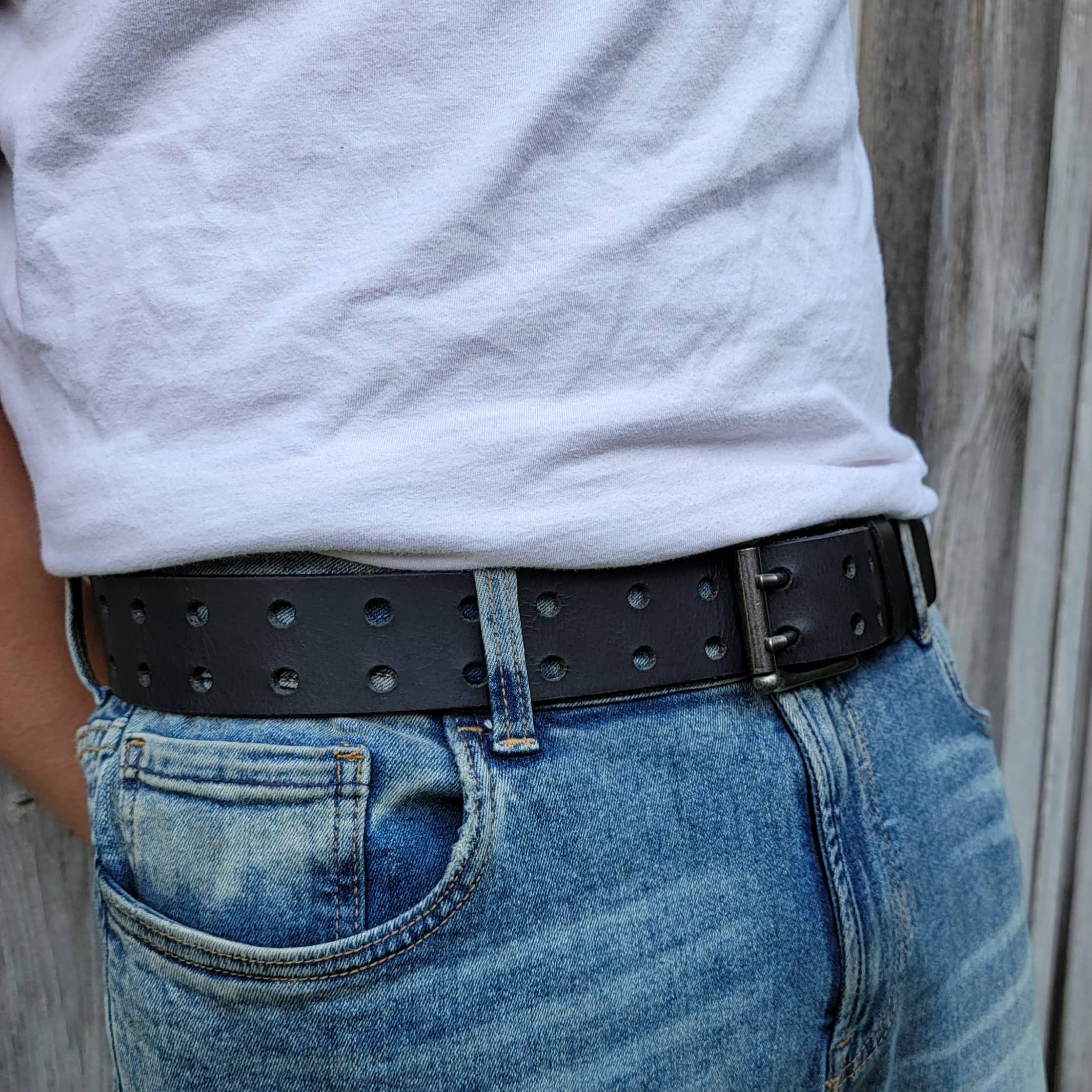 Black studded leather belt on blue jeans with white t-shirt, casual outdoor style