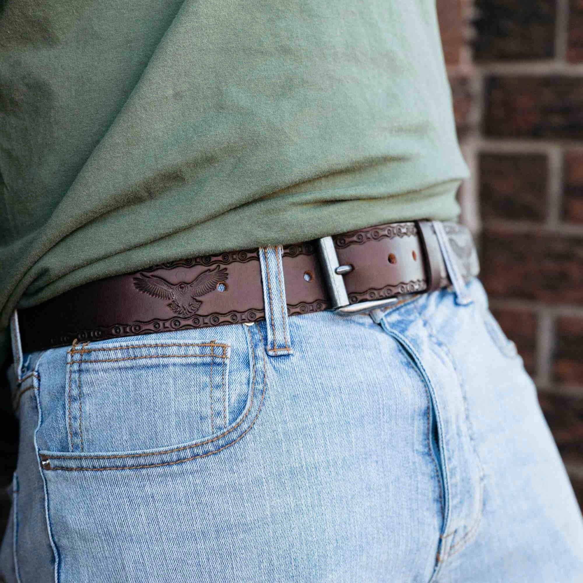 Brown leather eagle belt with embossed pattern worn with light blue jeans