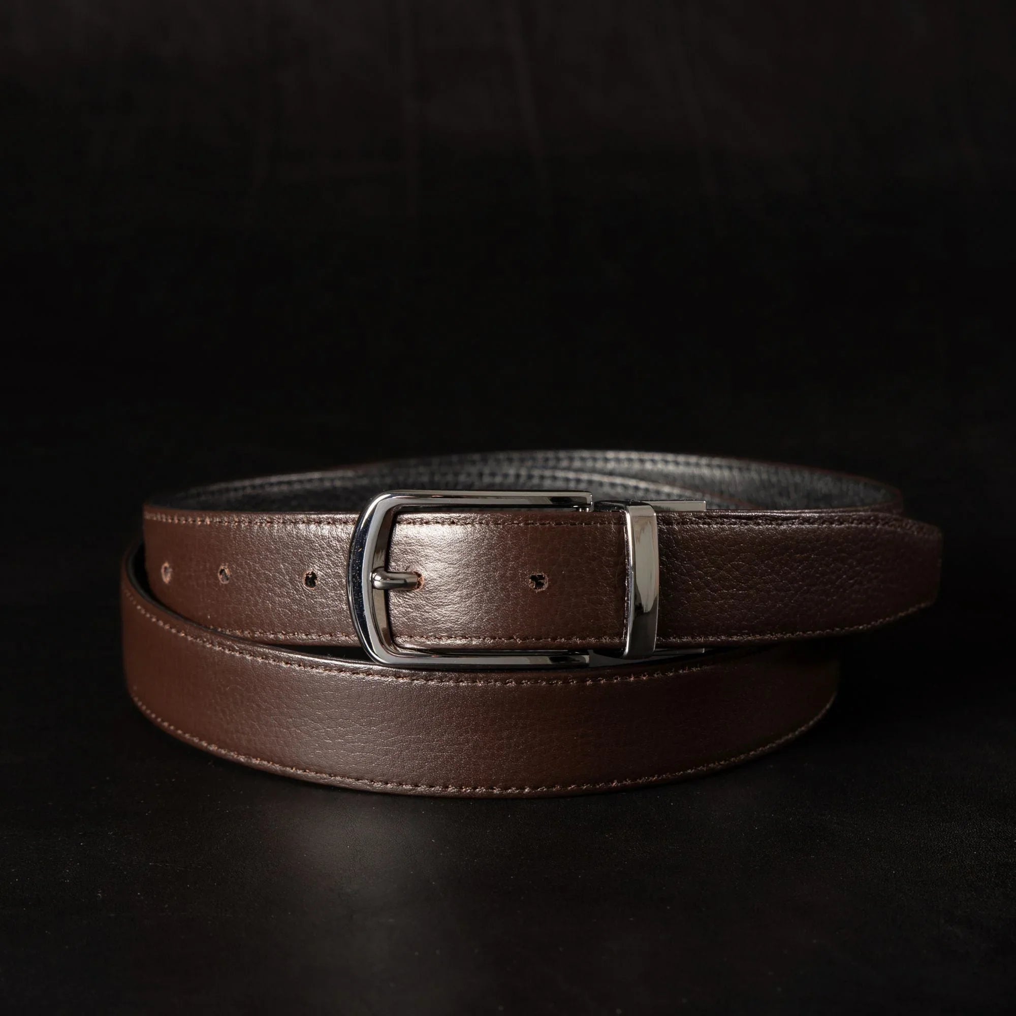 Dark brown leather belt with silver buckle on black background