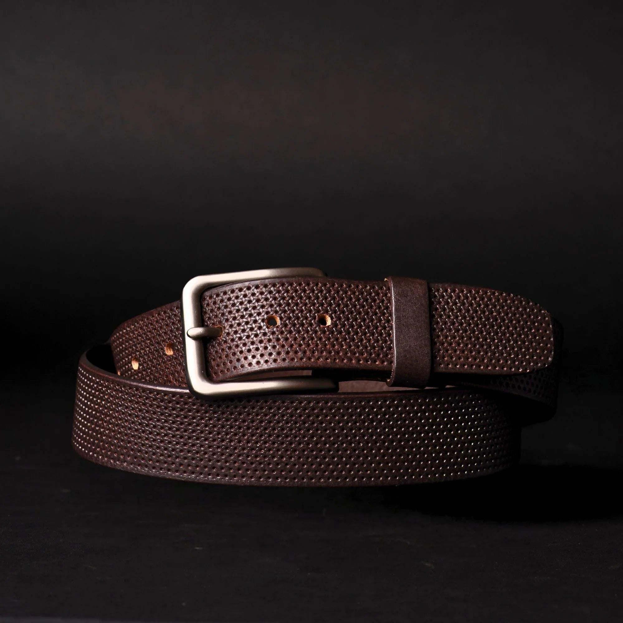 Brown textured leather belt with silver buckle on black background