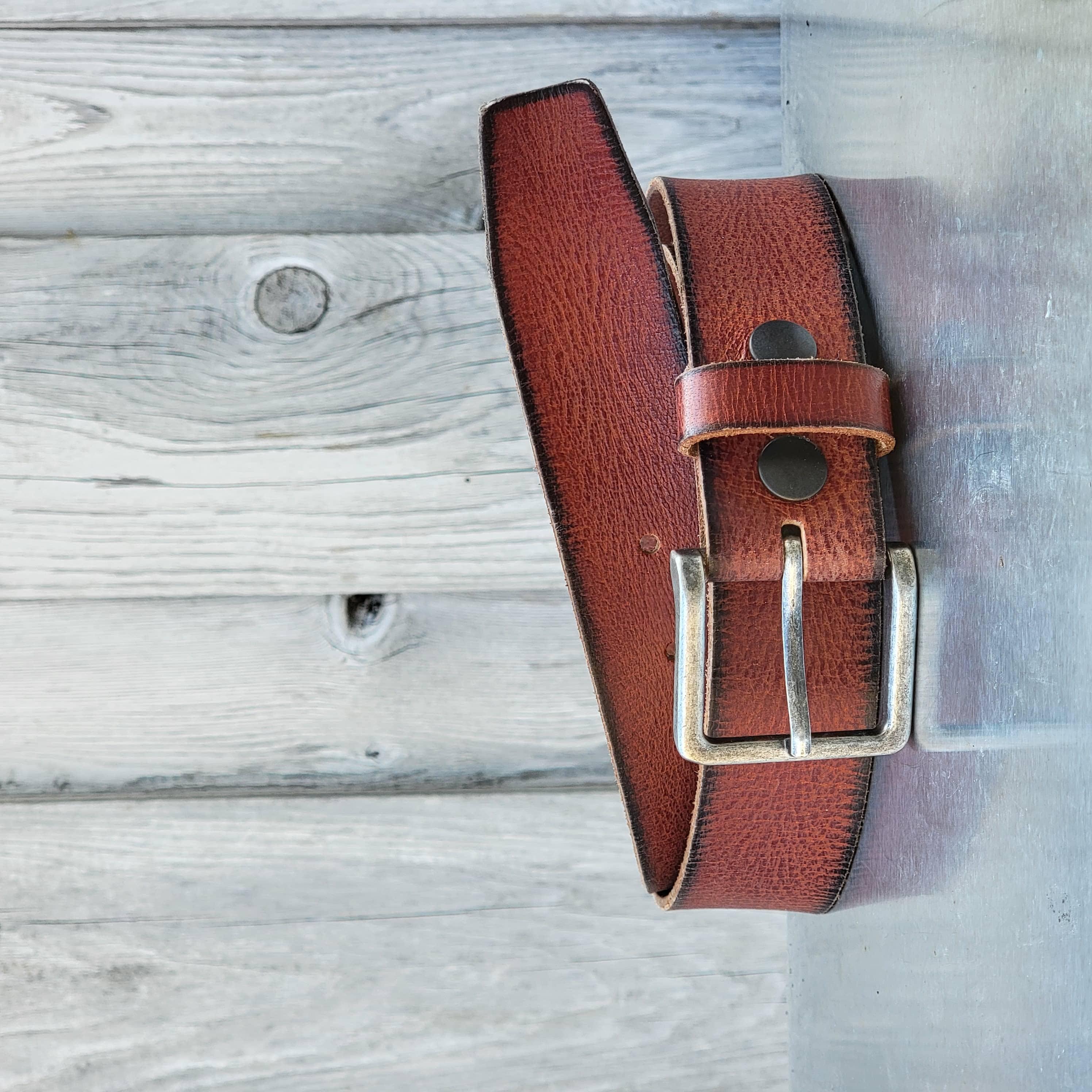 Brown leather belt with silver buckle against rustic wooden background