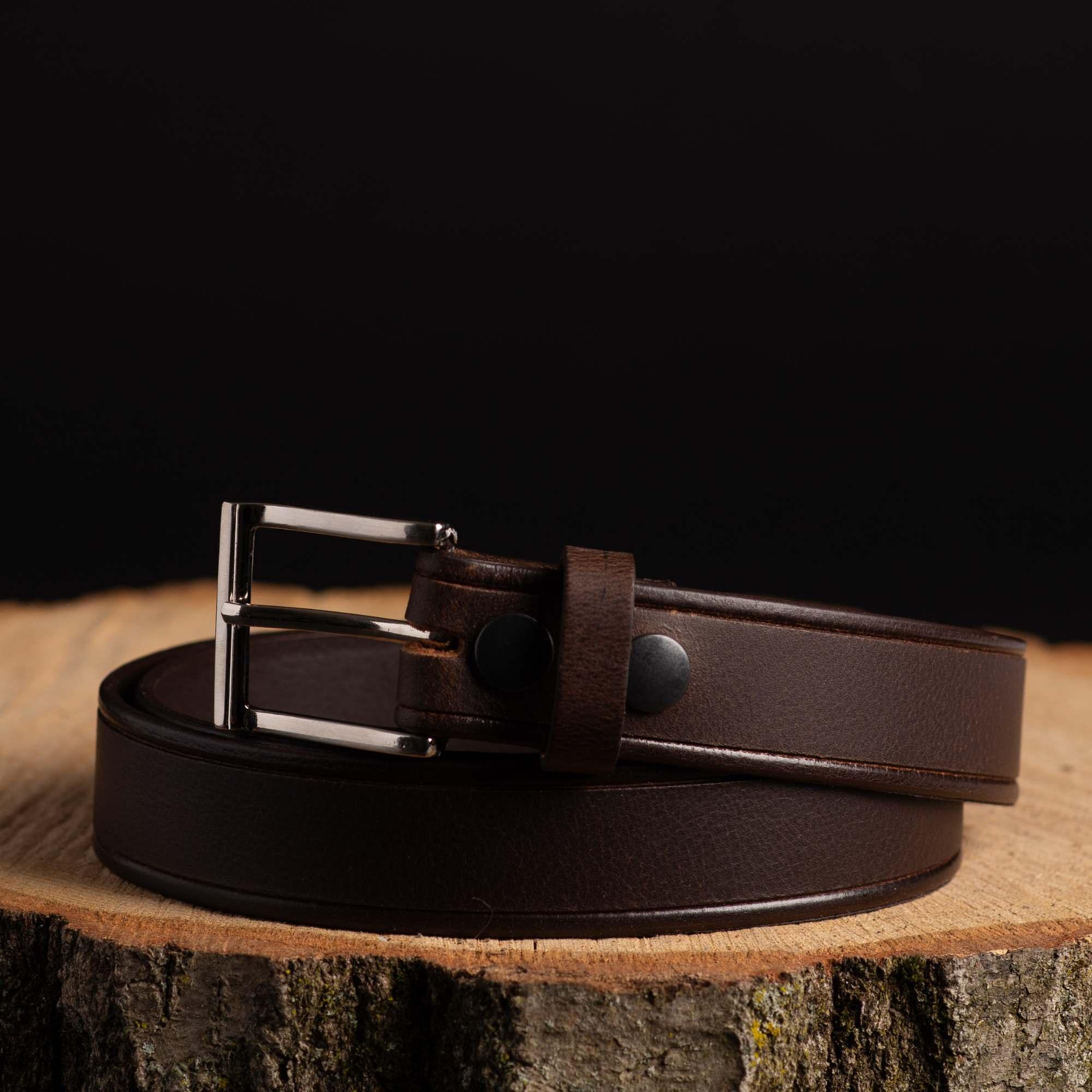 Brown leather belt with metal buckle on wood surface, product photo