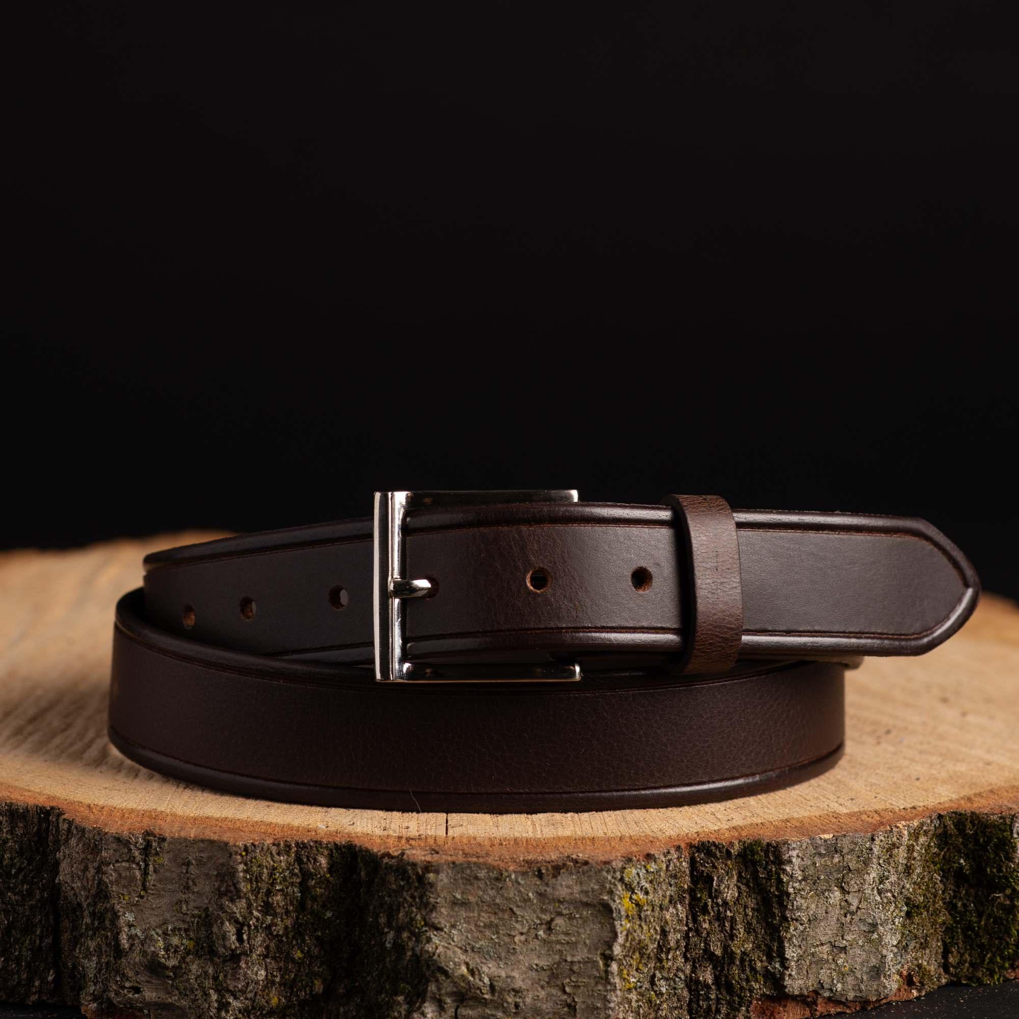 Dark brown leather belt with silver buckle on wooden slab, fashion accessory