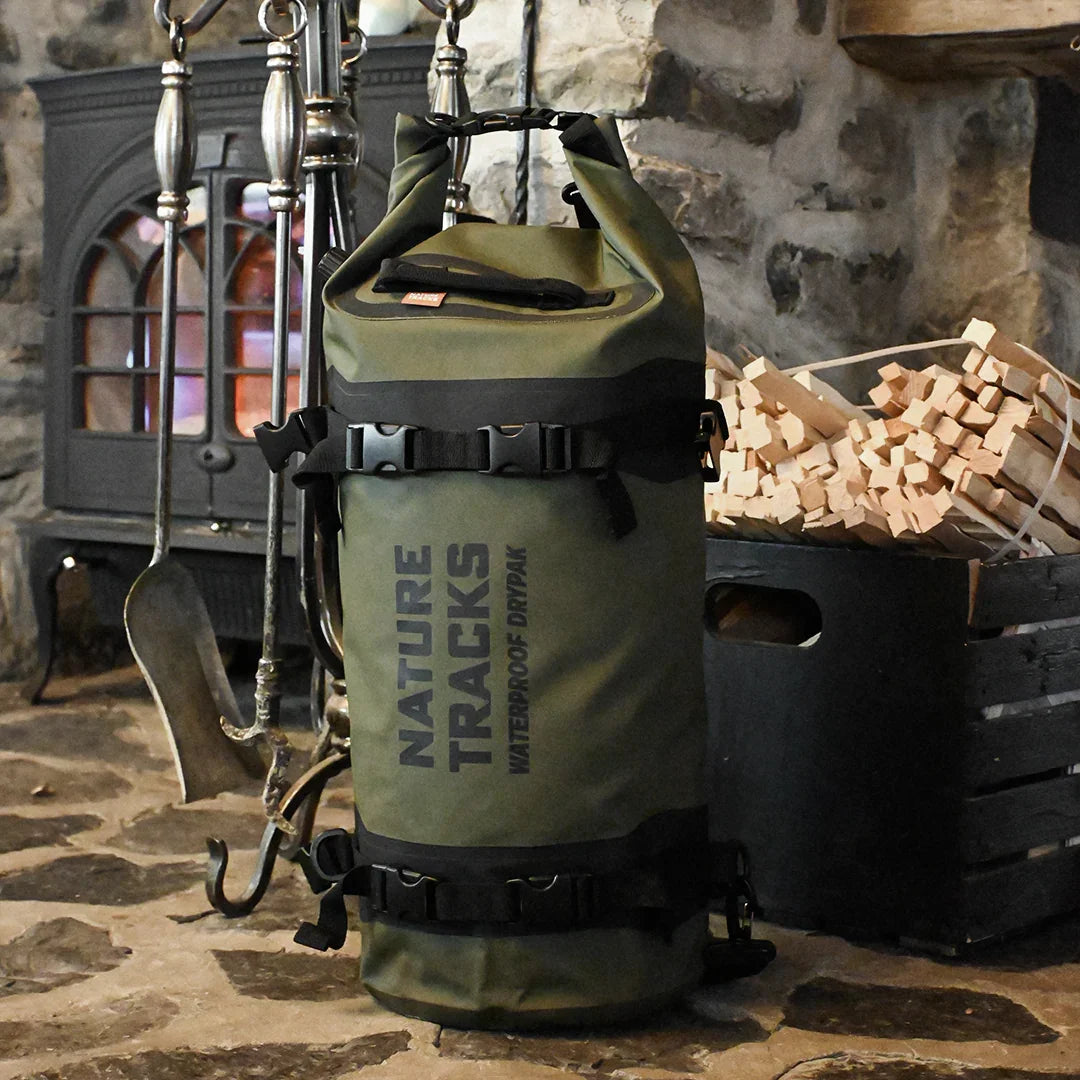 Green Nature Tracks waterproof dry bag on stone floor by fireplace and firewood crate