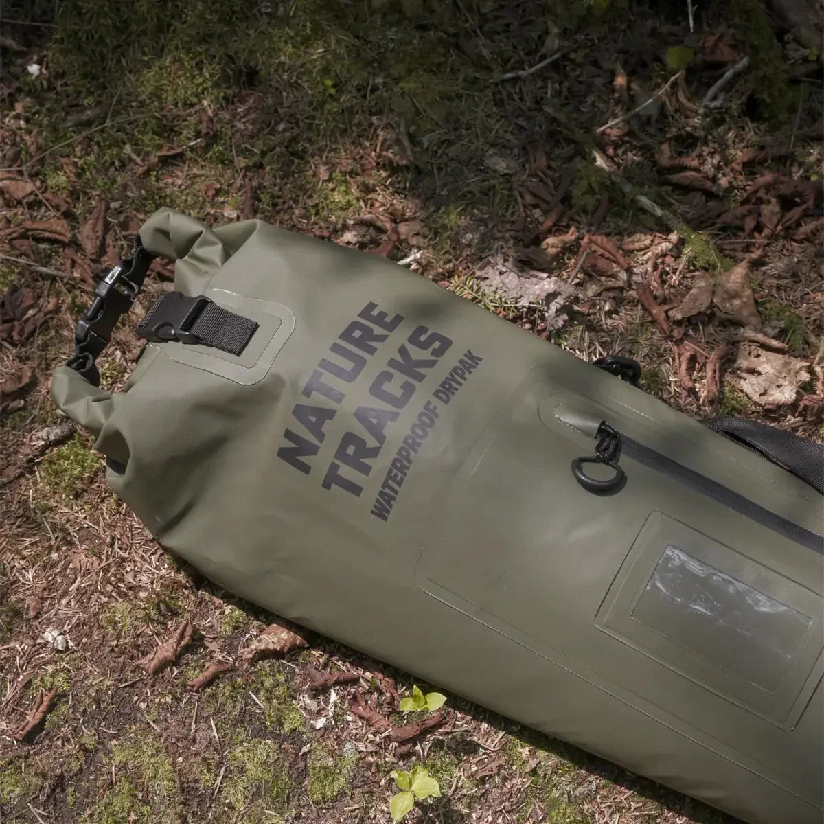 Nature Tracks waterproof dry bag on forest ground, olive green outdoor gear