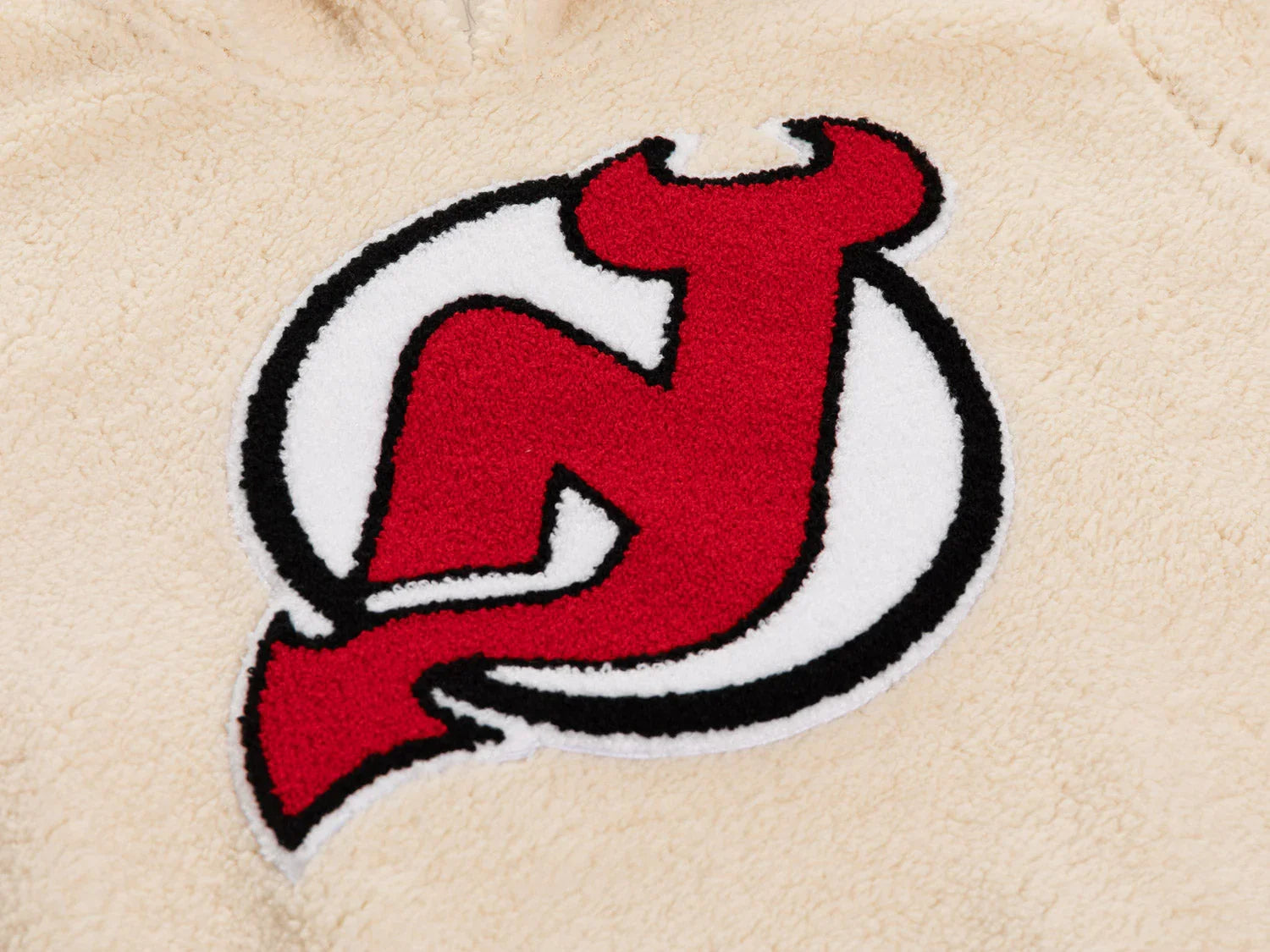 Red and white sports team logo on cream sherpa fleece fabric close-up
