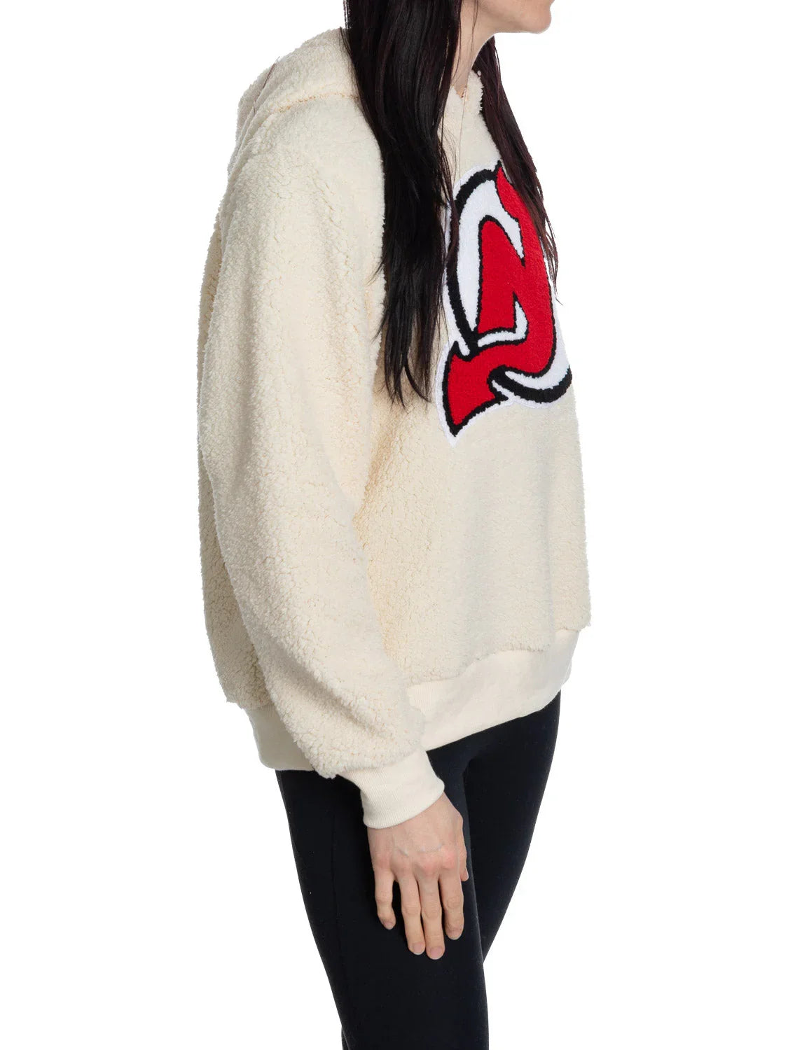 Woman in cream sherpa hoodie with large red New Jersey Devils logo, side view