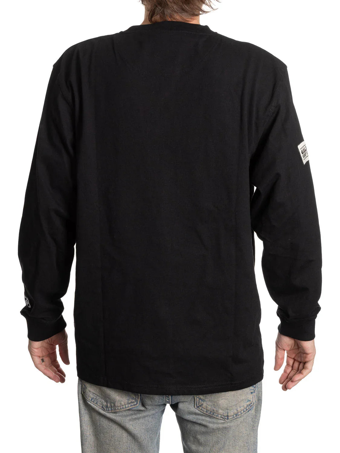 Back view of man wearing black long sleeve Henley shirt with patch detail, light jeans