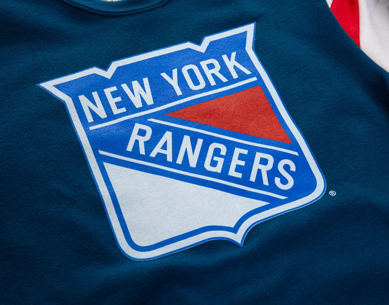 New York Rangers logo on blue fabric, close-up view of hockey sweatshirt design